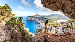 Capo Caccia, hiker admiring the view from a cave. Sardinia island, Ital