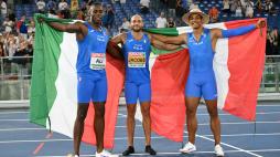 100m silver medallist Italy's athlete Chituru Ali, 100m gold medallist Italy's Lamont Marcell Jacobs and 110m hurdles gold medallist Italy's Lorenzo Ndele Simonelli pose with flags during the European Athletics Championships at the Olympic stadium in Rome on June 8, 2024. (Photo by Andreas SOLARO / AFP)