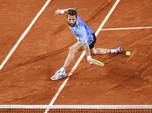 TOPSHOT - France's Corentin Moutet plays a backhand return to Austria's Sebastian Ofner during their men's singles match on Court Suzanne-Lenglen on day six of the French Open tennis tournament at the Roland Garros Complex in Paris on May 31, 2024. (Photo by EMMANUEL DUNAND / AFP)