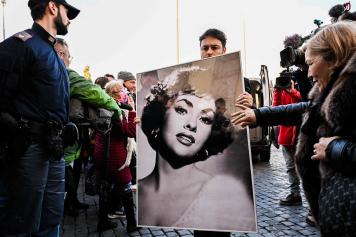 A woman touches a photo of late Italian actress Gina Lollobrigida brought by a funeral home employee for her funeral ceremony at Piazza del Popolo in Rome on January 19, 2023. - Italian actress Gina Lollobrigida, one of the last icons of the Golden Age of Hollywood, has died aged 95, culture minister Gennaro Sangiuliano said on Twitter on January 16. (Photo by Alberto PIZZOLI / AFP)