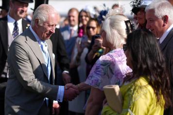 Britain's King Charles III shakes hands with a guest during a Royal Garden Party at Buckingham Palace, central London, on May 8, 2024. (Photo by Jordan Pettitt / POOL / AFP)