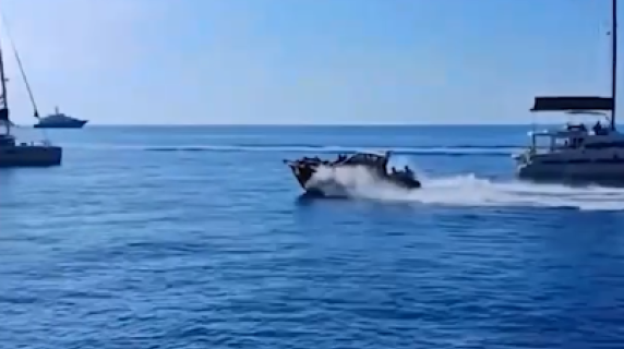 Sfreccia a tutta velocità tra le barche ferme in rada vicino alla scogliera di Capri