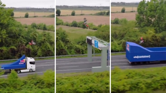 L'acrobazia del biker di freestyle motocross: il salto mortale in volo tra due tir in movimento
