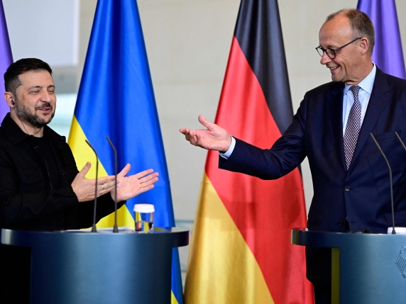 Ukrainian President Volodymyr Zelensky (L) and German Chancellor Friedrich Merz react as they address a joint press conference after a video conference of European leaders with the US President on the Ukraine war ahead of a summit between the US a...