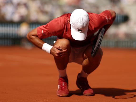 PARIS, FRANCE - JUNE 03: Novak Djokovic of Serbia holds his knee during his match against Francisco Cerundolo of Argentina in the Men's Singles fourth round match during Day Nine of the 2024 French Open at Roland Garros on June 03, 2024 in Paris, France. (Photo by Clive Brunskill/Getty Images)