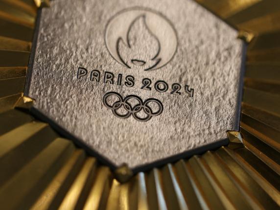 TOPSHOT - This photograph taken on January 30, 2024 in Paris shows the upcoming Paris 2024 Olympics gold medal designed by Fench luxury jewellery house Chaumet. On the medals' head side, the engraved figures of the goddess of victory Athena, Nike, the Panathenaic stadium and the Acropolis are imposed by the International Olympic Committee (IOC) but Paris 2024 has obtained exceptional authorization to add the design of the Eiffel Tower, and use 18 grams of Eiffel Tower metal on each medal, extracted from pieces of the tower. (Photo by Thomas SAMSON / AFP)