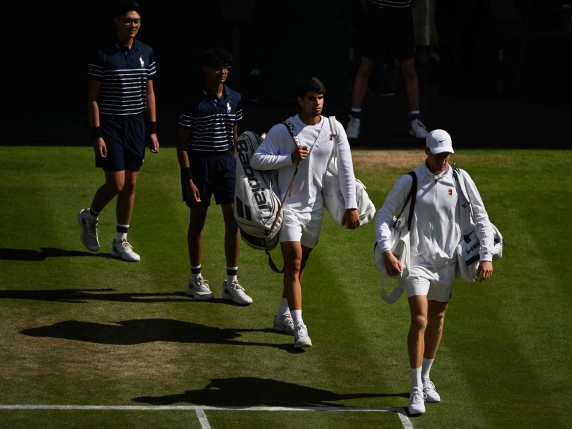 Spain's Carlos Alcaraz (C) and Italy's Jannik Sinner (R) arrive on court for their men's singles final tennis match on the fourteenth day of the 2025 Wimbledon Championships at The All England Lawn Tennis and Croquet Club in Wimbledon, southwest London, on July 13, 2025. (Photo by Glyn KIRK / AFP) / RESTRICTED TO EDITORIAL USE