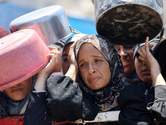 Palestinians wait at a lentil soup distribution point in Gaza City in the northern Gaza Strip on July 27, 2025. (Photo by Omar AL-QATTAA / AFP)