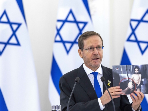 Israel's President Isaac Herzog shows photos of Israeli citizens imprisoned in the Gaza Strip during a joint statement with Lithuania's President Gitanas Nauseda at the Presidential palace in Vilnius, Lithuania, Monday, Aug. 4, 2025. (AP Photo/Min...
