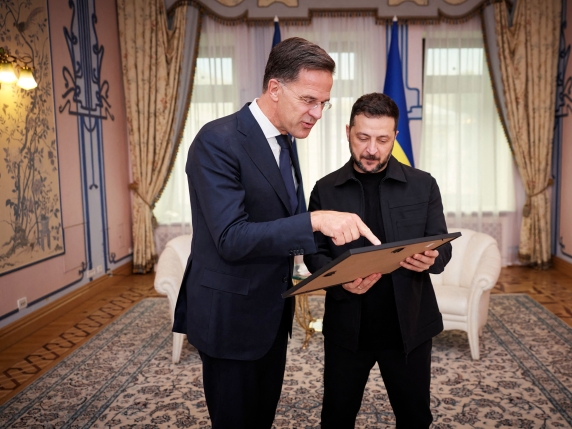 This handout photograph taken and released by the Ukrainian Presidential Press Service on August 22, 2025, shows Ukraine's President Volodymyr Zelensky (R) and Secretary General of NATO Mark Rutte looking at a framed family photo of the recent mee...