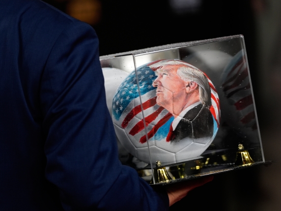 A person carries a soccer ball with a picture of President Donald Trump before the draw for the 2026 soccer World Cup at the Kennedy Center in Washington, Friday, Dec. 5, 2025. (AP Photo/Julia Demaree Nikhinson)