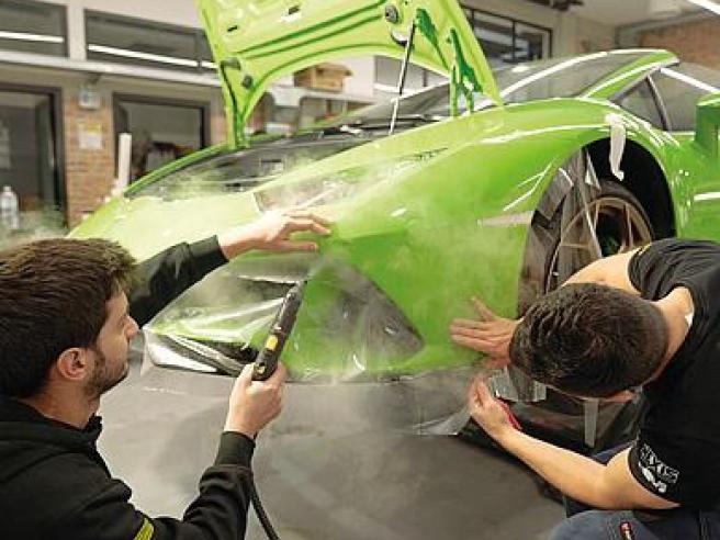 Auto wrapping, uomo con spatola installa pellicola o pellicola protettiva  in vinile sul cofano. Il lavoratore fa i dettagli automatici. Rivestimento  di protezione per vernici per automobili, prof Foto stock - Alamy