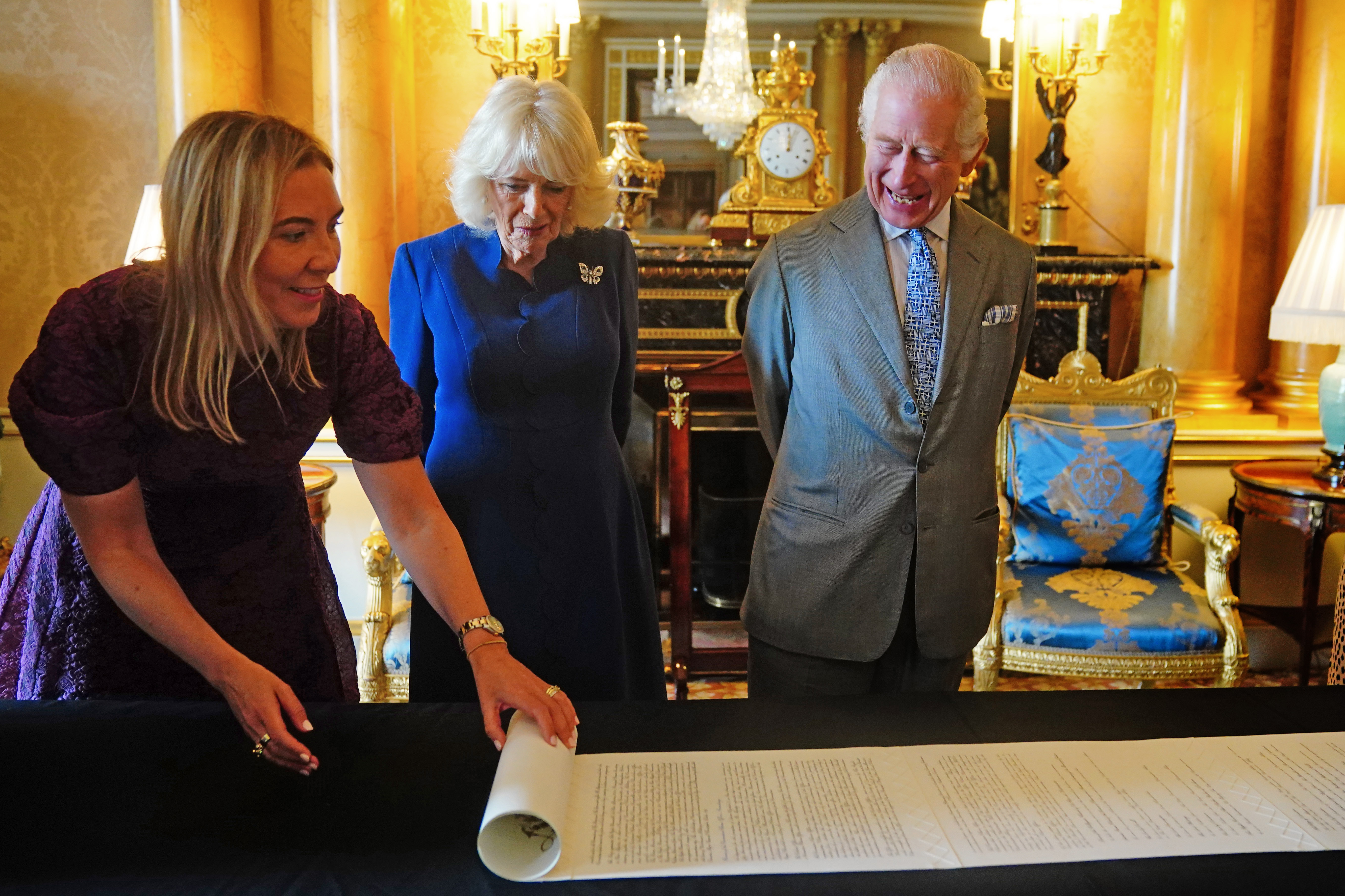 LONDON, ENGLAND - MAY 1: King Charles III and Queen Camilla are presented with the Coronation Roll, an official record of their Coronation, by the Clerk of the Crown in Chancery, Antonia Romeo (L), at Buckingham Palace on May 1, 2024 in London, England. (Photo by Victoria Jones - WPA Pool/Getty Images)