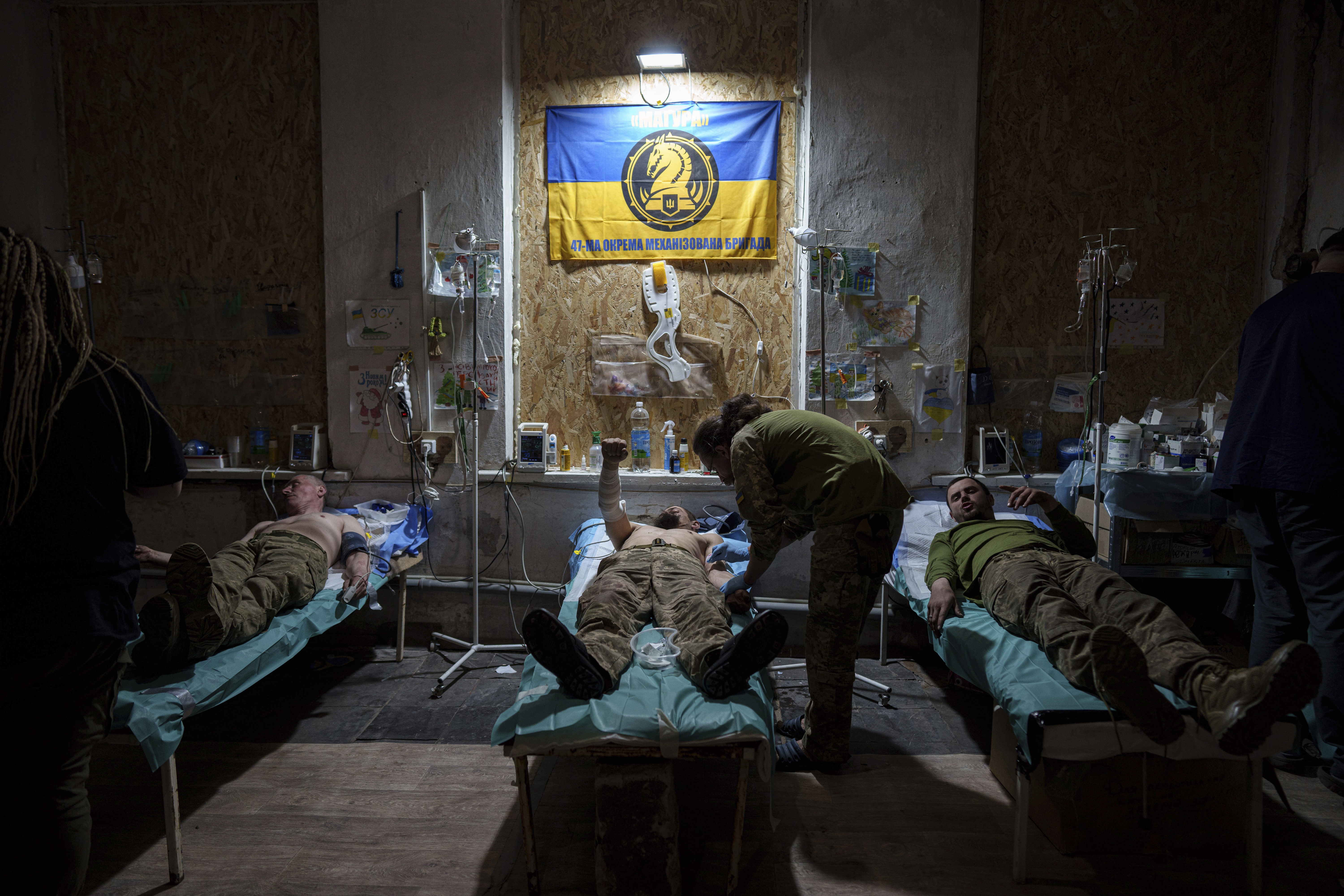 A Ukrainian military medic of the 47th Brigade treats his injured comrades at the field hospital in Avdiivka direction, Donetsk region, Ukraine, Friday, May 10, 2024. (AP Photo/Evgeniy Maloletka)