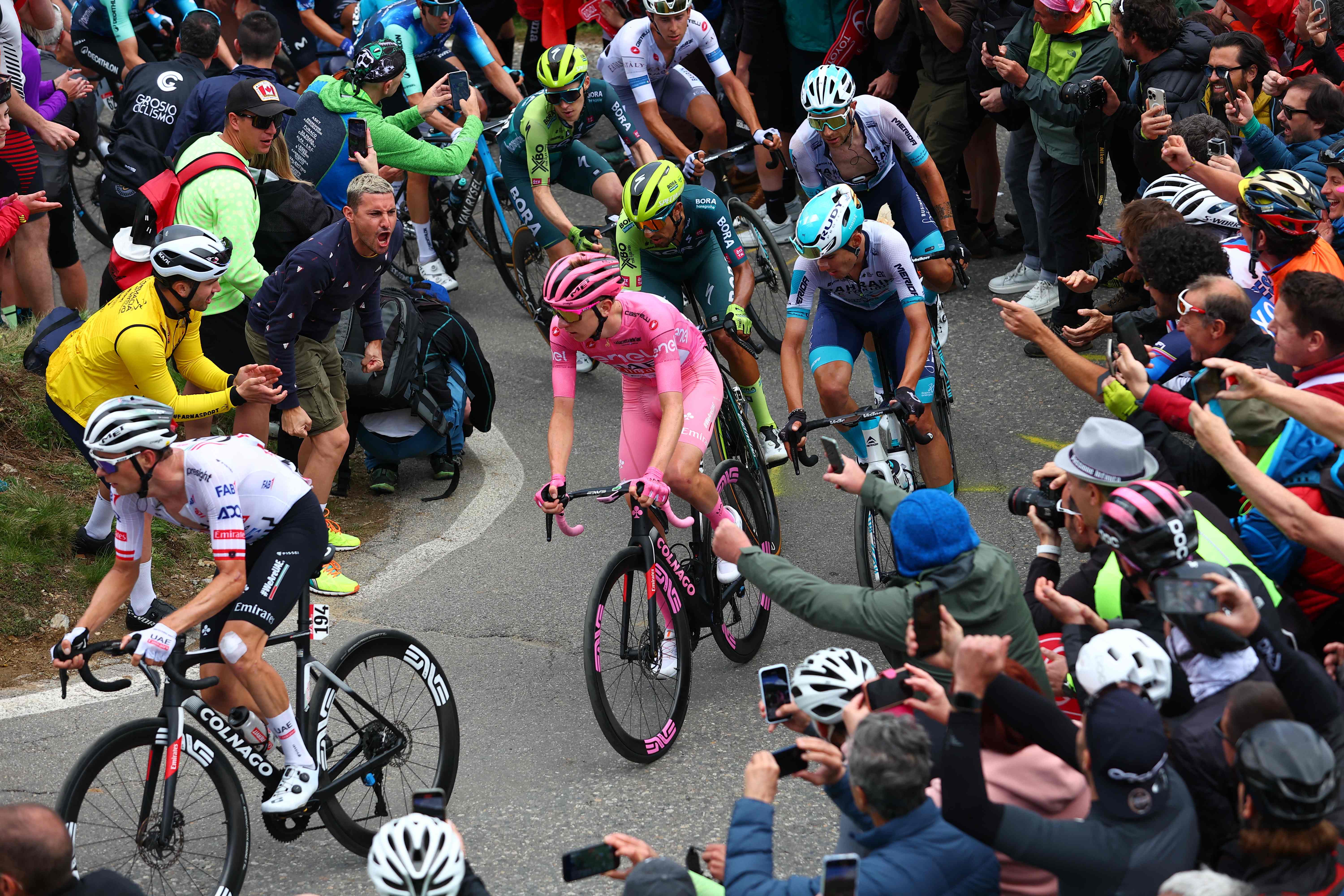 Pink jersey Team UAE's Slovenian rider Tadej Pogacar (C) climbs the Mortirolo section surrounded by fans during the 15th stage of the 107th Giro d'Italia cycling race, 222km between Manerba del Garda and Mottolino on May 19, 2024. (Photo by Luca Bettini / AFP)