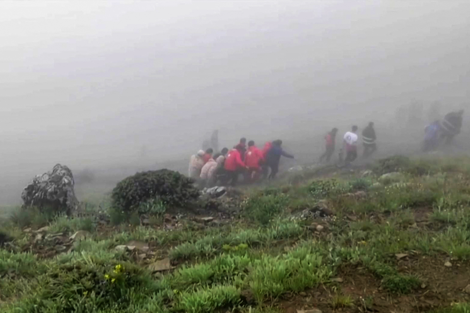TOPSHOT - This grab taken from handout video footage released by the Iranian Red Cescent on May 20, 2024 shows rescuers recovering bodies at the site of President Ebrahim Raisi's helicopter crash in a fog-shrouded mountainous area of northwest Iran. Iranian President Ebrahim Raisi was declared dead on May 20, 2024, after rescue teams found his crashed helicopter in a fog-shrouded western mountain region, sparking mourning in the Islamic republic. (Photo by Iranian Red Crescent / AFP) / Israel OUT / RESTRICTED TO EDITORIAL USE - MANDATORY CREDIT  AFP/HO/IRANIAN RED CRESCENT - NO RESALE -  - NO MARKETING NO ADVERTISING CAMPAIGNS  -NO ACCESS ISRAEL MEDIA/PERSIAN LANGUAGE TV STATIONS OUTSIDE IRAN/ STRICTLY NO ACCESS BBC PERSIAN/ VOA PERSIAN/ MANOTO-1 TV/ IRAN INTERNATIONAL/RADIO FARDA /