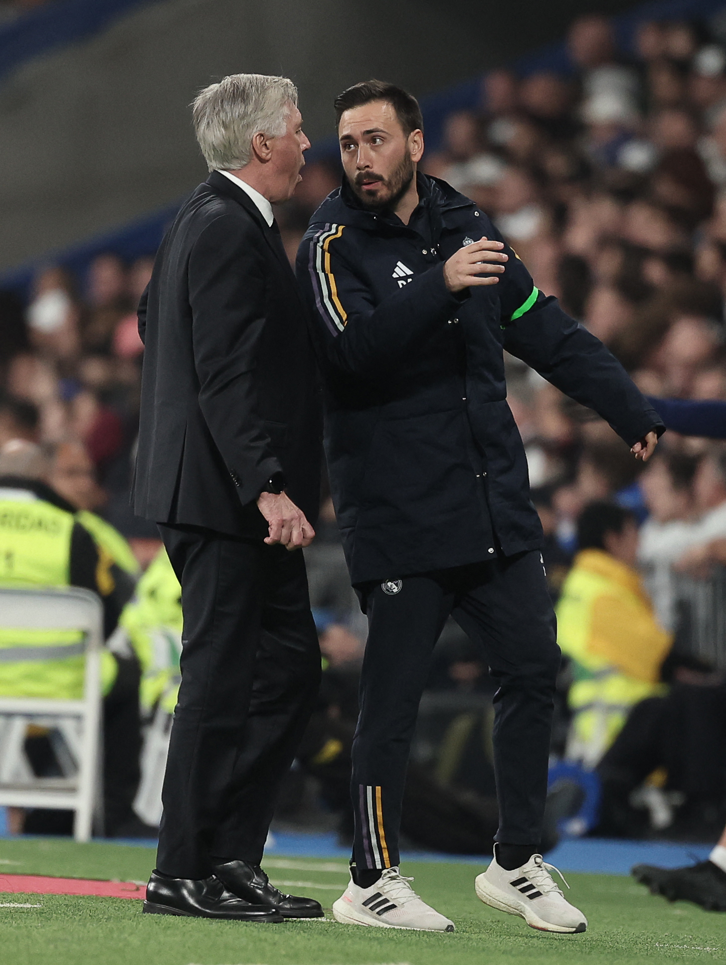 Real Madrid's Italian coach Carlo Ancelotti (L) speaks with Real Madrid's Italian assistant coach Davide Ancelotti during the Spanish league football match between Real Madrid CF and Club Atletico de Madrid at the Santiago Bernabeu stadium in Madrid on February 4, 2024. (Photo by Thomas COEX / AFP)