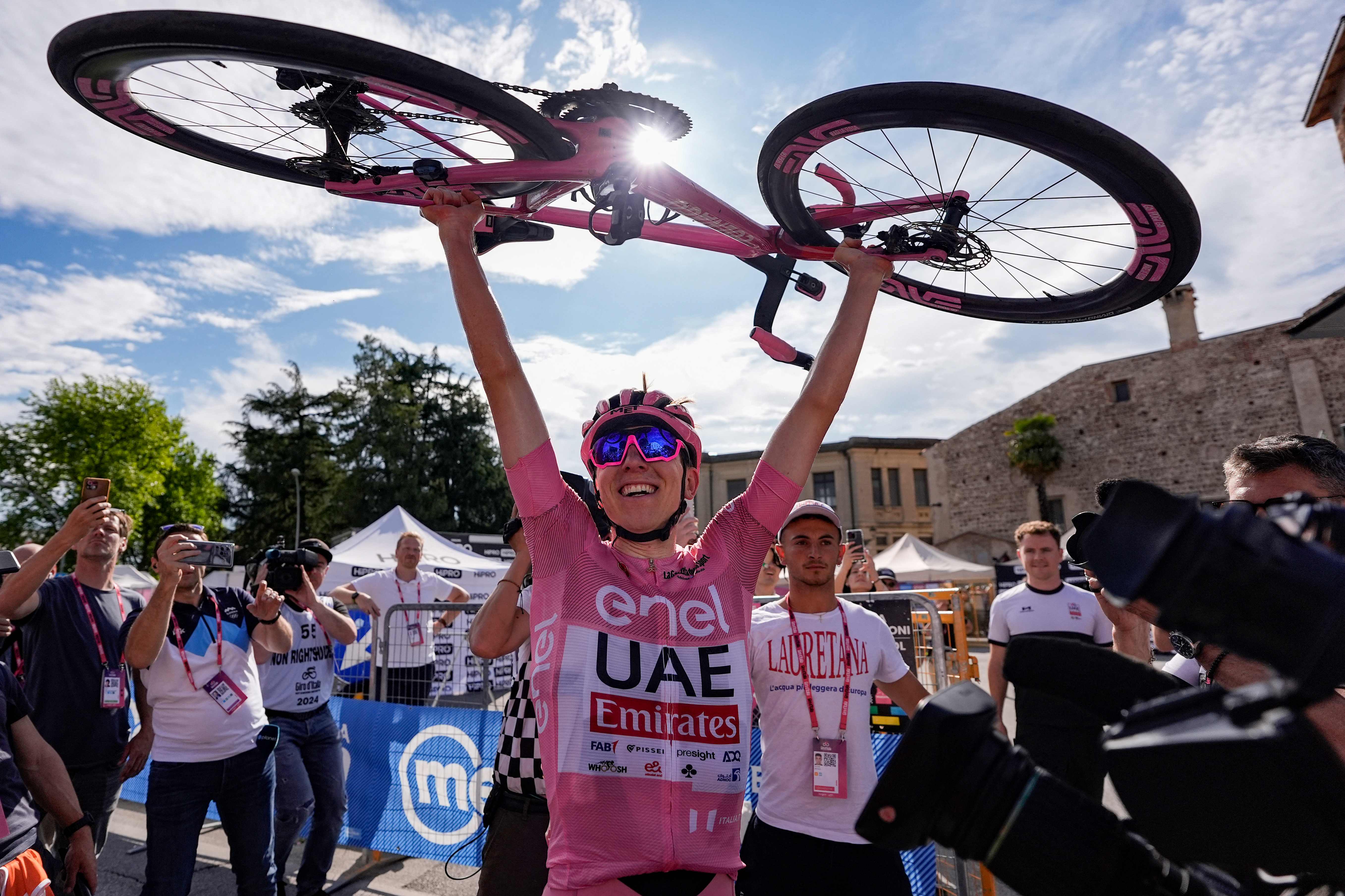 Team UAE's Slovenian rider Tadej Pogacar wearing the overall leader's pink jersey lifts up with bicycle as he celebrates after crossing the finish line to win the 20th stage of the 107th Giro d'Italia cycling race, 184km between Alpago and Bassano del Grappa on May 25, 2024. (Photo by FABIO FERRARI / POOL / AFP)