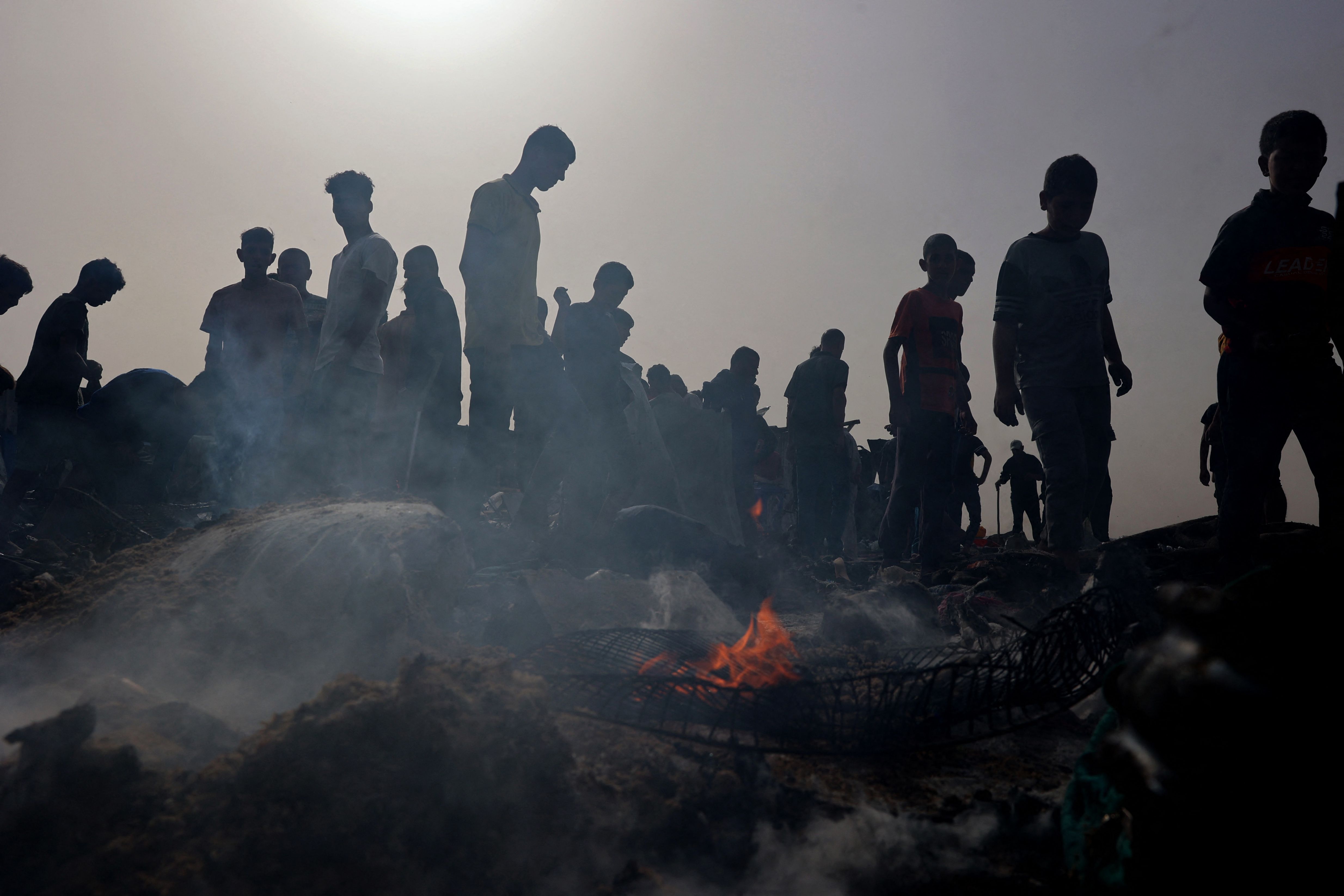 TOPSHOT - Palestinians gather at the site of an Israeli strike on a camp for internally displaced people in Rafah on May 27, 2024, amid ongoing battles between Israel and the Palestinian Hamas militant group. The Palestinian Authority and the militant group Hamas said Israeli strikes on a centre for displaced people killed dozens near the southern city of Rafah on May 26, while the Israeli army said it had targeted Hamas militants. (Photo by Eyad BABA / AFP)