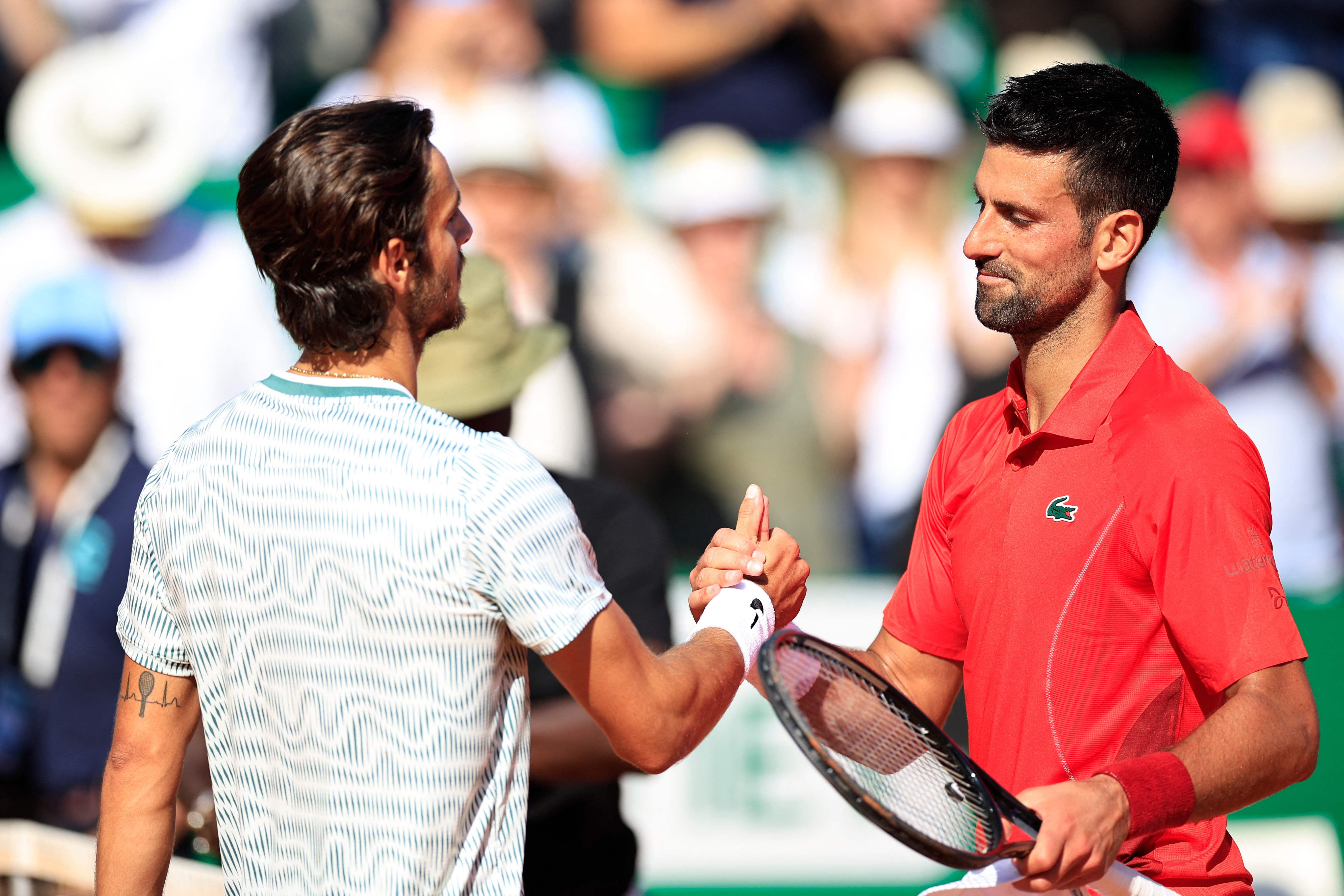 Serbia's Novak Djokovic (R) shakes hands with Italy's Lorenzo Musetti after winning at the end of their Monte Carlo ATP Masters Series Tournament round of 16 tennis match on the Rainier III court at the Monte Carlo Country Club on April 11, 2024. (Photo by Valery HACHE / AFP)