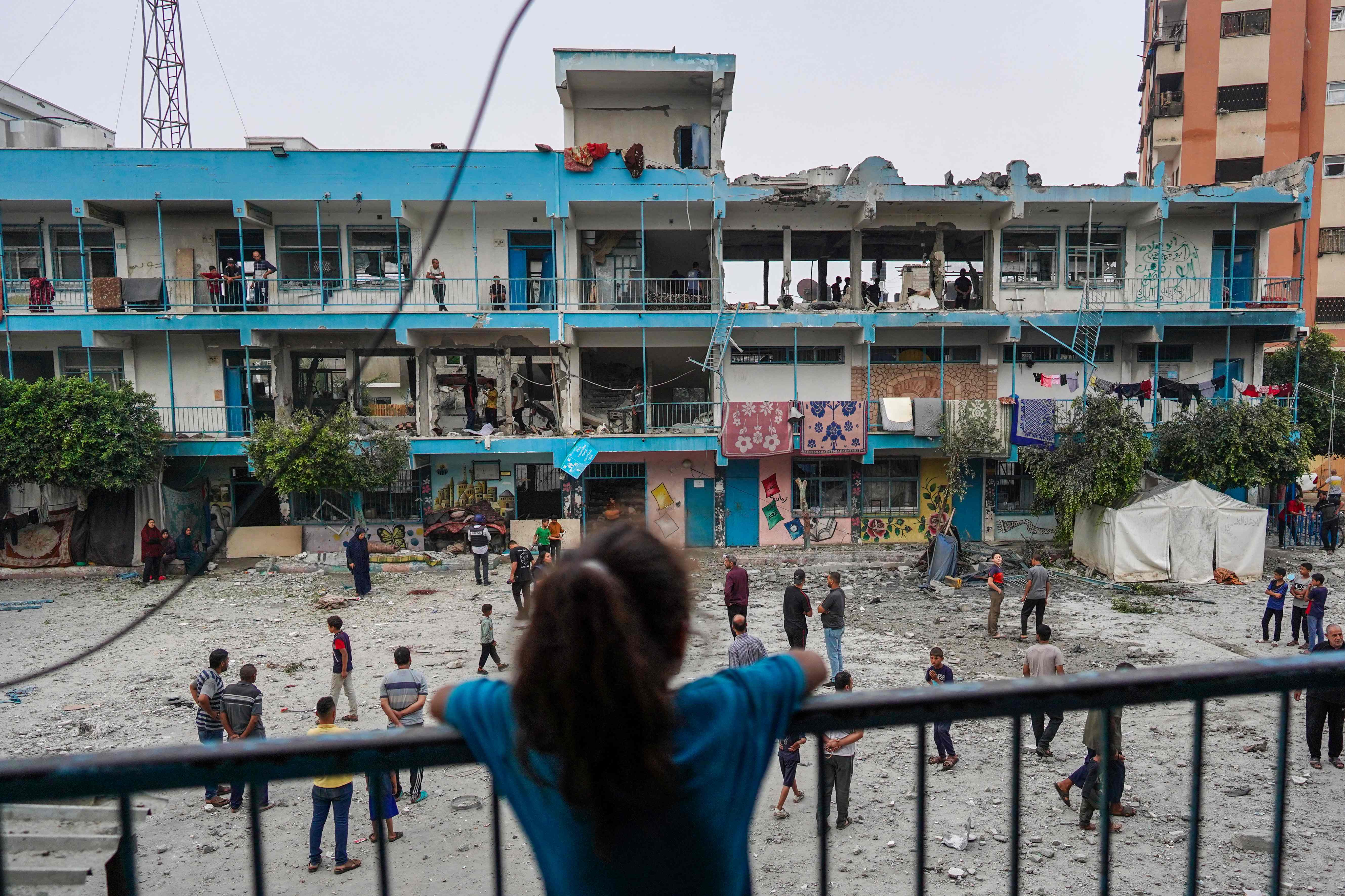 TOPSHOT - A Palestinian girl watches as others check a UN-school housing displaced people that was hit during Israeli bombardment in Nuseirat, in the central Gaza Strip, on June 6, 2024, amid the ongoing conflict between Israel and the Palestinian Hamas militant group. The Israeli military said on June 6 its fighter jets had struck a UN-run school used by Palestinian militants in central Gaza, with authorities in the Hamas-run territory reporting at least 27 dead. (Photo by Bashar TALEB / AFP)