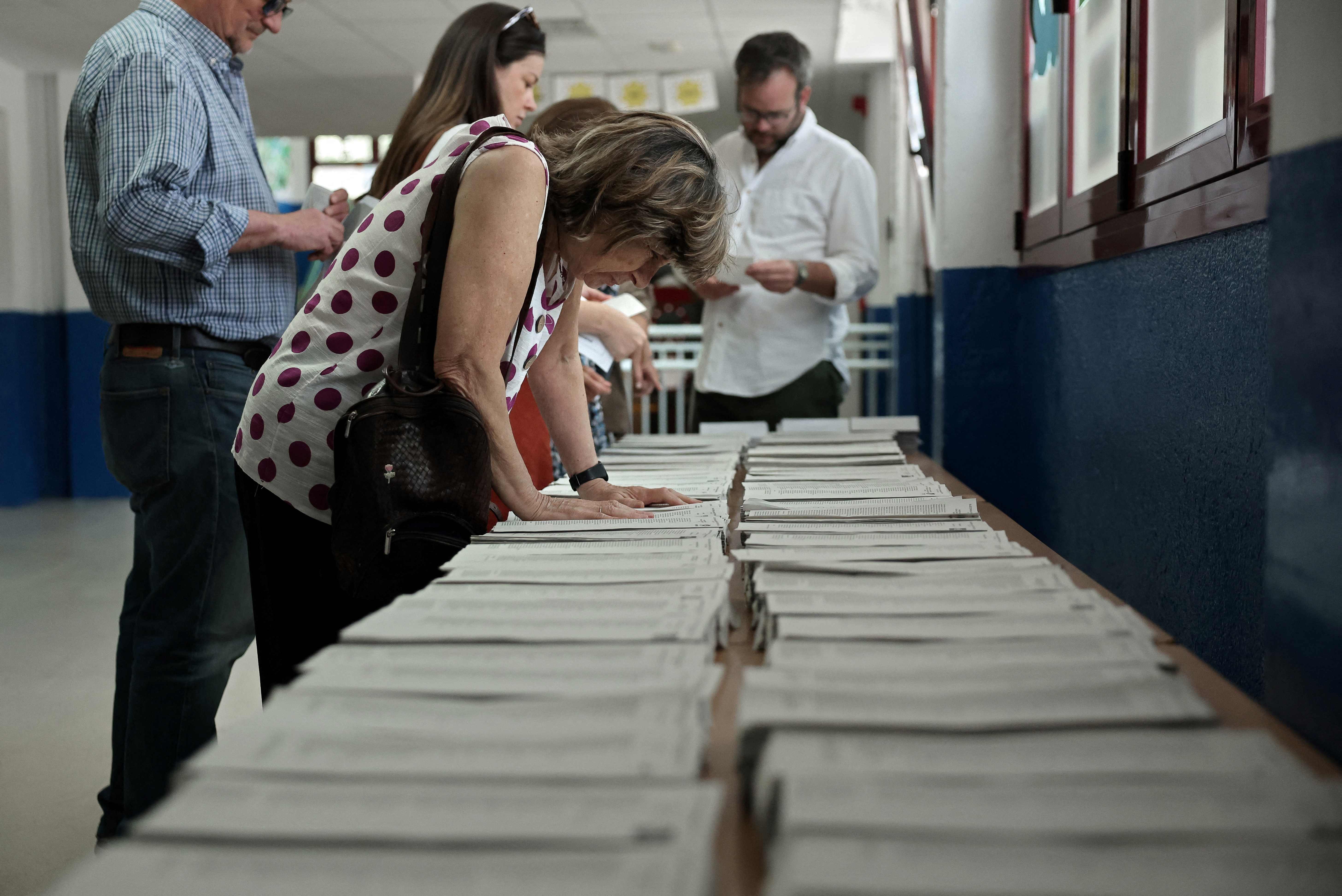Voters pick their ballot for the European Parliament elections at a polling station in Madrid, on June 9, 2024. Voting began across Europe on the final -- and biggest -- day of marathon EU elections, with balloting due in 21 countries, where support for surging far-right parties is being tested. (Photo by Thomas COEX / AFP)