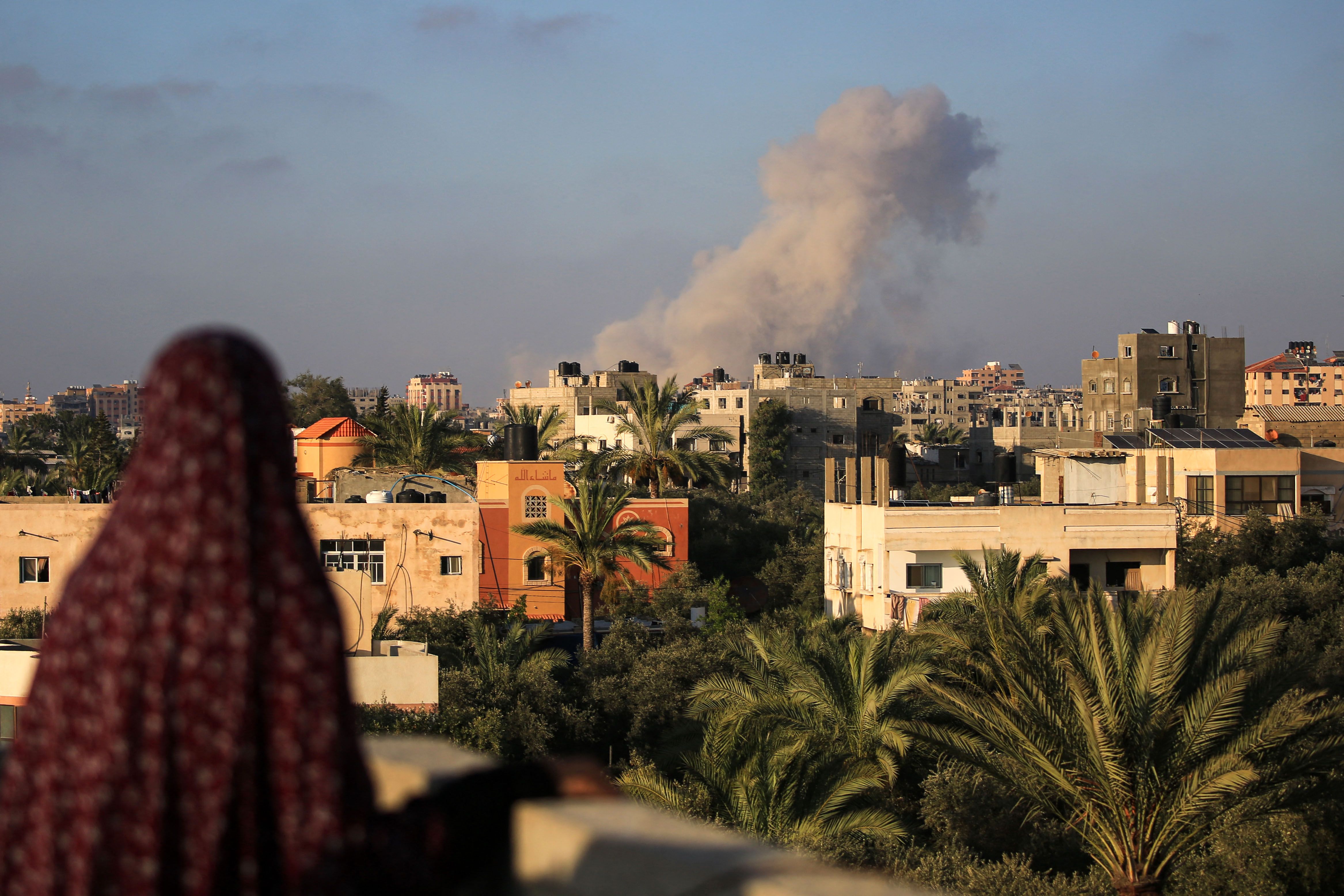 TOPSHOT - A Palestinian woman watches as smoke billows following an Israeli strike south of Gaza City, in the town of al-Zawaida in the central Gaza Strip, on June 11, 2024 amid the ongoing conflict between Israel and the Palestinian militant group Hamas. (Photo by Eyad BABA / AFP)