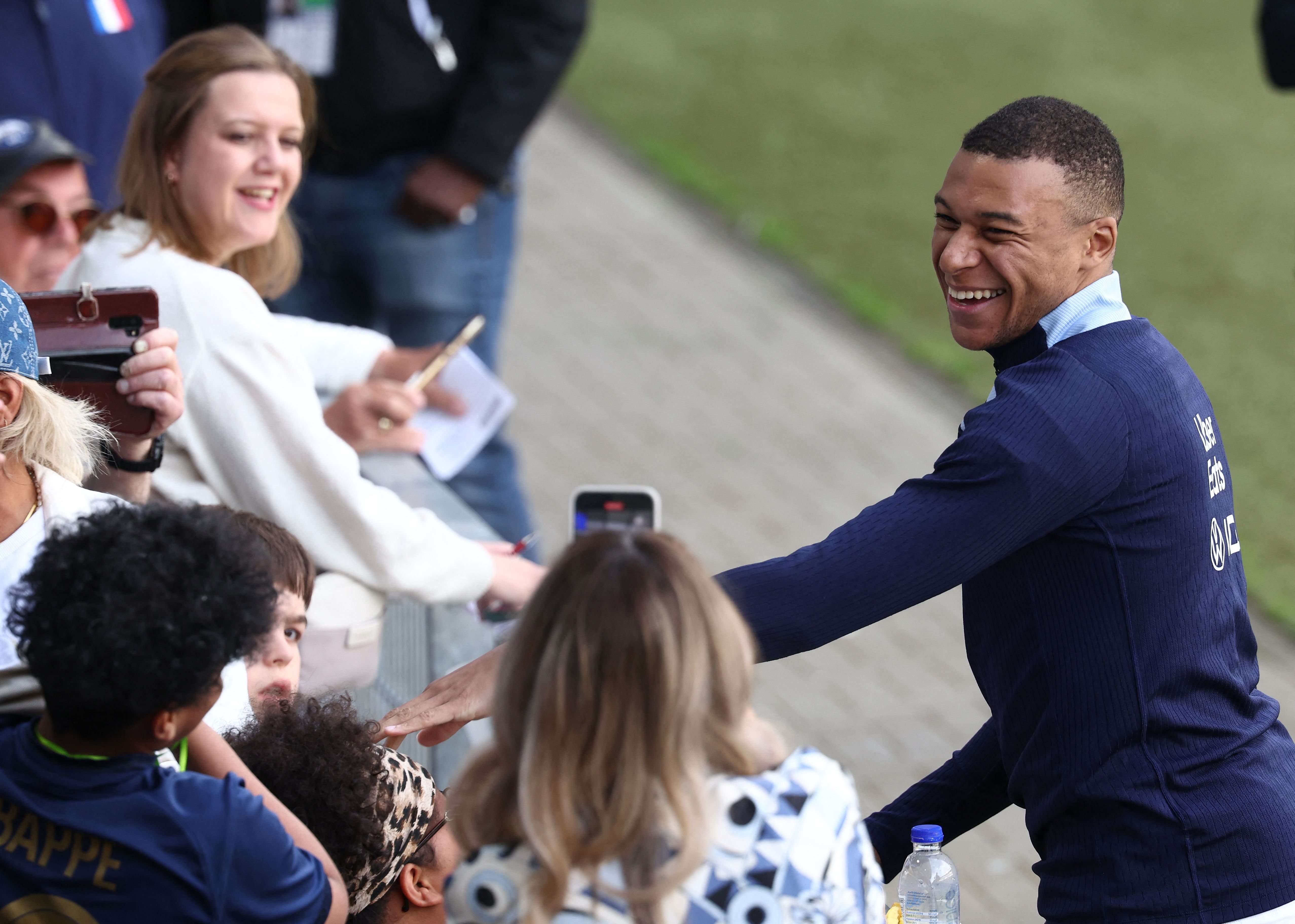 France's forward #10 Kylian Mbappe (R)  reacts with  fans  at the end of a training session at the Home Deluxe Arena Stadium in Paderborn, western Germany, on June 13, 2024, ahead of the UEFA Euro 2024 football championship. (Photo by FRANCK FIFE / AFP)