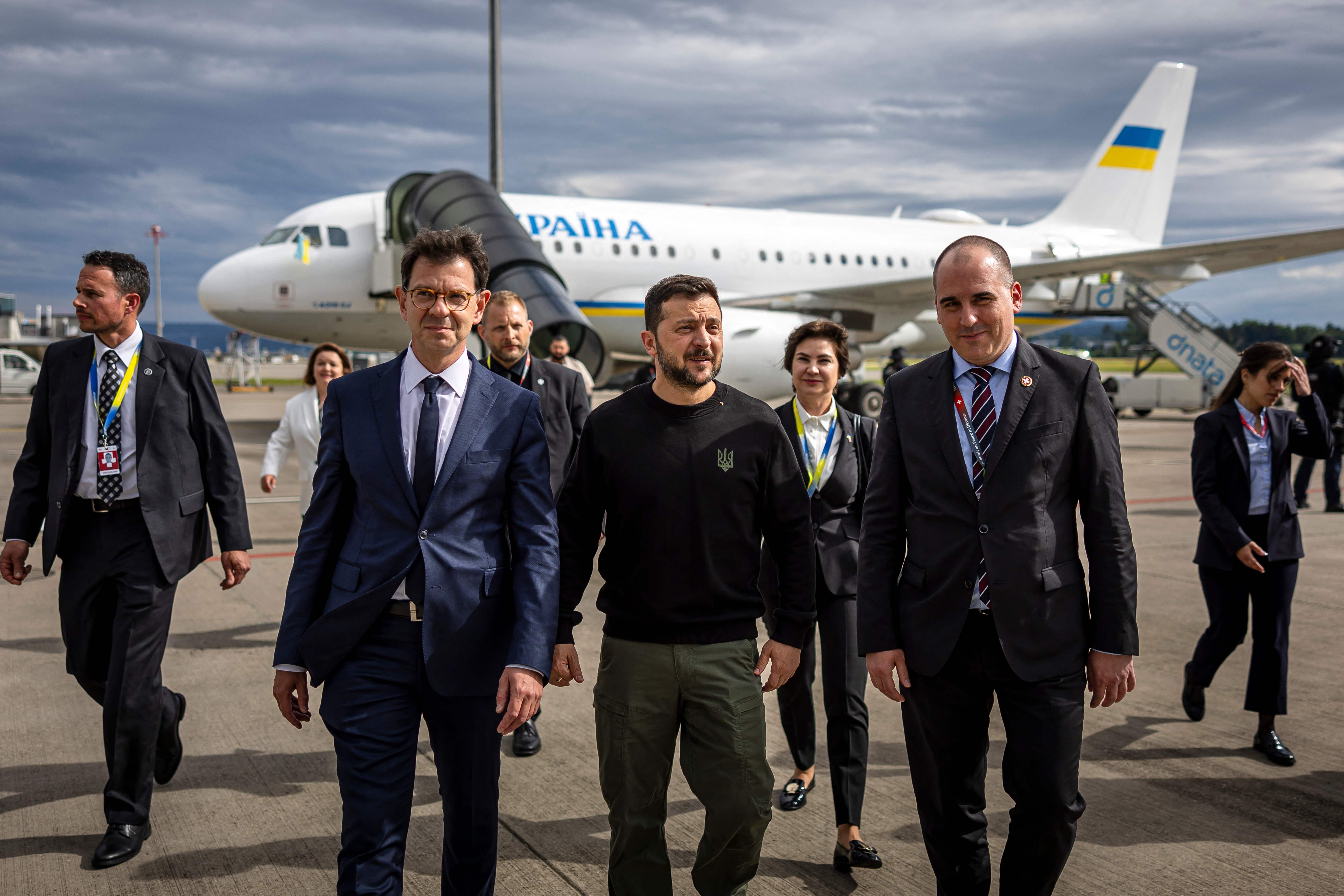 Ukraine's President Volodymyr Zelensky (C) is welcomed by Switzerland's Ambassador to Ukraine Felix Baumann (L) and Deputy Head of Swiss Protocol Manuel Irman (R) as he arrives at the Zurich airport on June 14, 2024, ahead of the  Ukraine Peace Summit in Switzerland. World leaders from countries around the world will gather in the luxury Burgenstock resort, central Switzerland this weekend to try to work out a way towards a peace process for Ukraine -- albeit without Russia. (Photo by MICHAEL BUHOLZER / POOL / AFP)