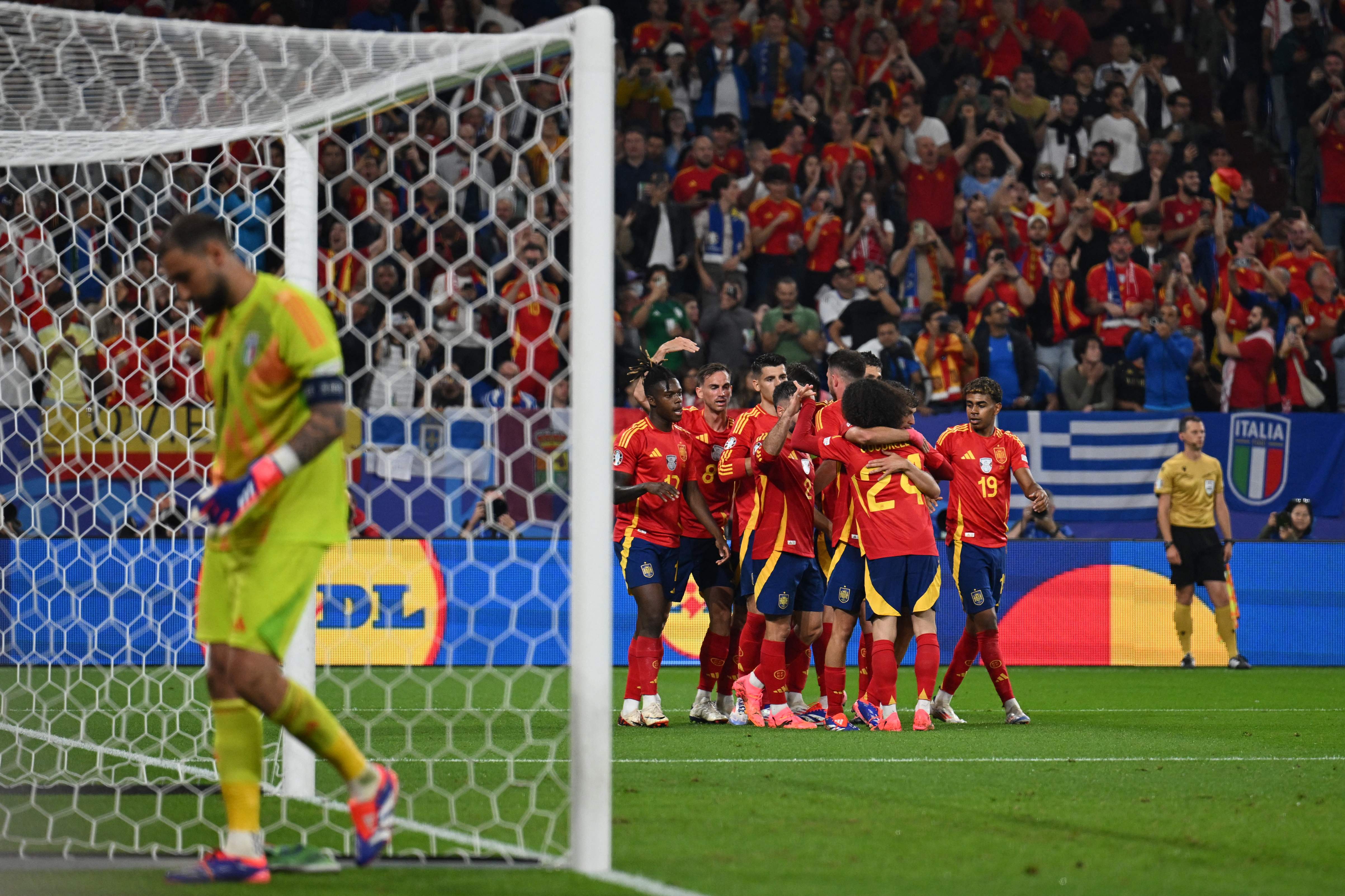 Spain's players celebrate next to Italy's goalkeeper #01 Gianluigi Donnarumma (L) after an own goal giving Spain the lead during the UEFA Euro 2024 Group B football match between Spain and Italy at the Arena AufSchalke in Gelsenkirchen on June 20, 2024. (Photo by OZAN KOSE / AFP)