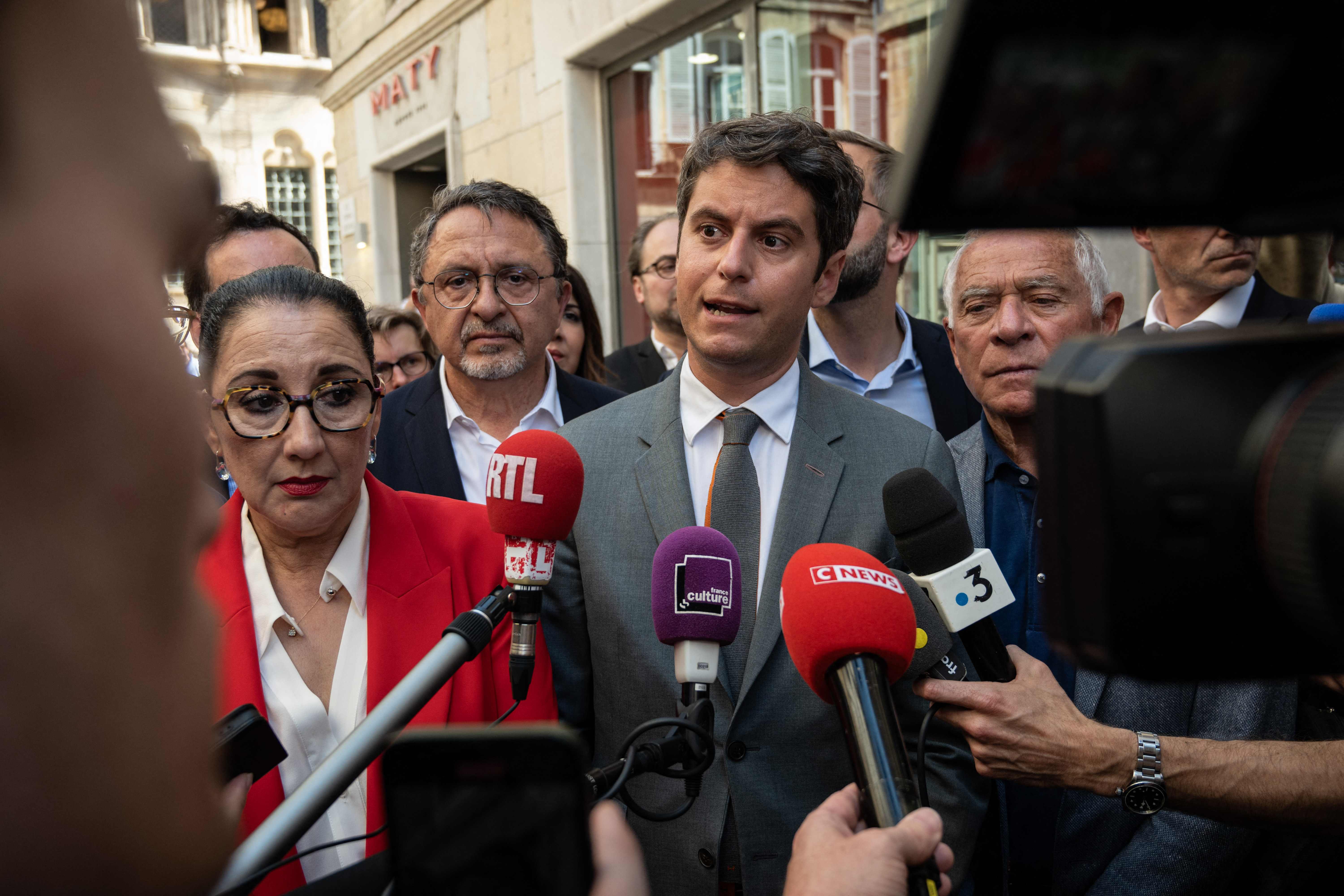 Frances Prime Minister Gabriel Attal (C) speaks to journalists during a campaign visit to support outgoing deputies of Cote-d'Or and candidates for the general elections of the ruling party "Renaissance" Minister Fadila Khattabi (L)? Didier Martin (2NDl° and François Patriat (R) in Dijon, eastern France, on June 24, 2024. The president surprised the country by dissolving parliament after the far right trounced his centrist party in EU Parliament elections earlier this month. (Photo by ARNAUD FINISTRE / AFP)
