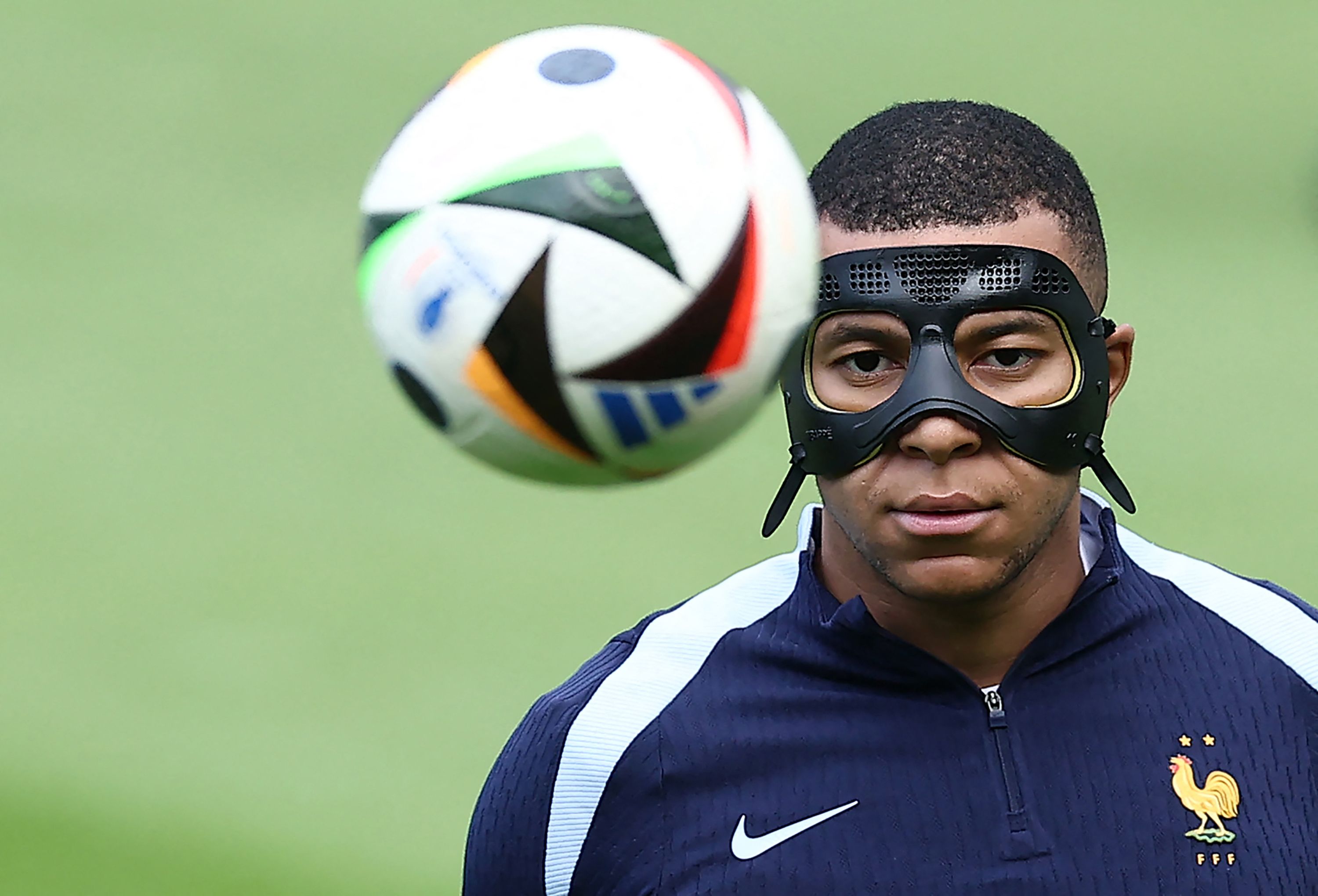 France's forward #10 Kylian Mbappe, wearing a protective mask, eyes the ball during a training session  training session at the Home Deluxe Arena Stadium in Paderborn, western Germany, on June 23, 2024, during of the UEFA Euro 2024 football championship. (Photo by FRANCK FIFE / AFP)
