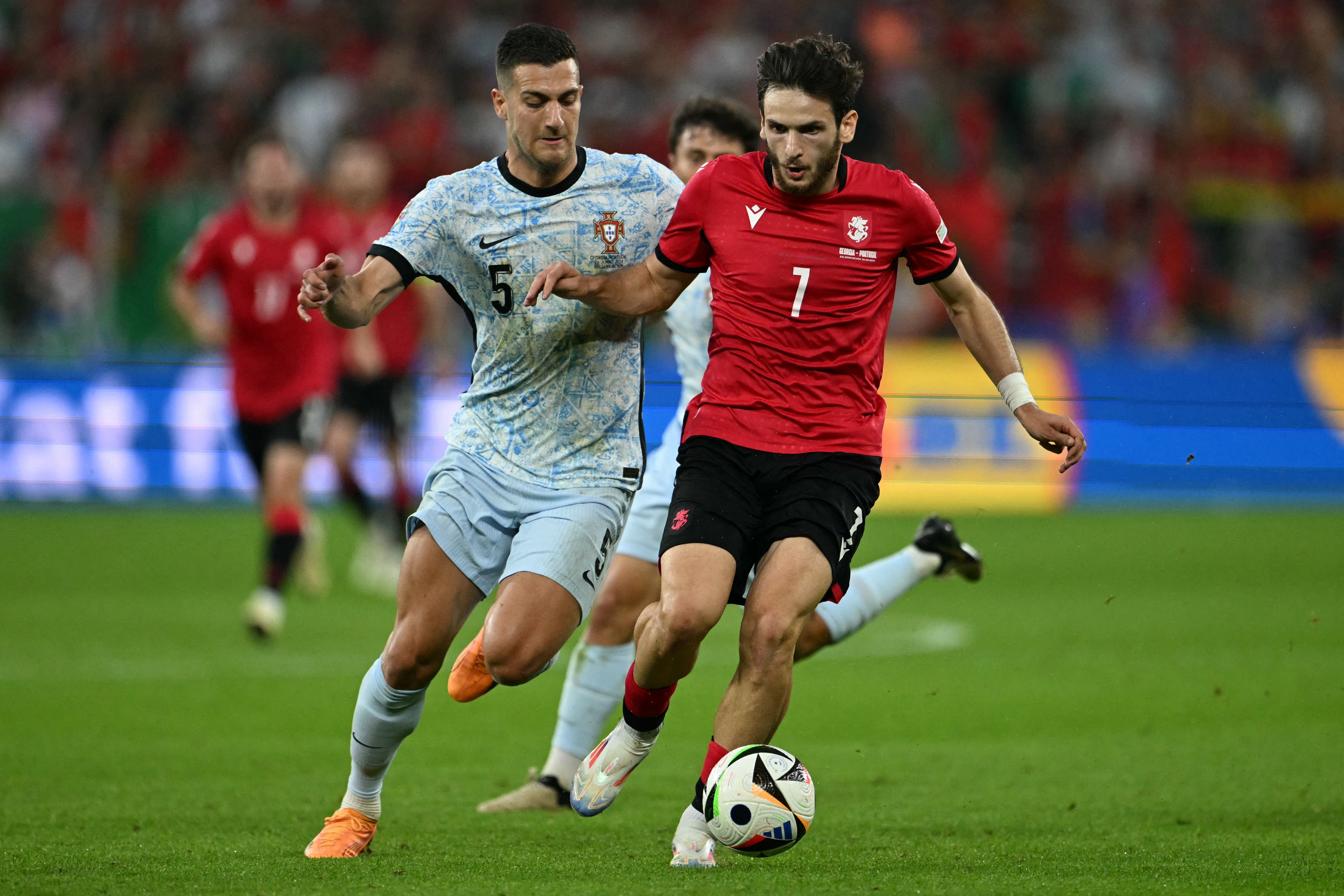 (From L) Portugal's defender #05 Diogo Dalot and Georgia's forward #07 Khvicha Kvaratskhelia vie for the ball during the UEFA Euro 2024 Group F football match between Georgia and Portugal at the Arena AufSchalke in Gelsenkirchen on June 26, 2024. (Photo by OZAN KOSE / AFP)