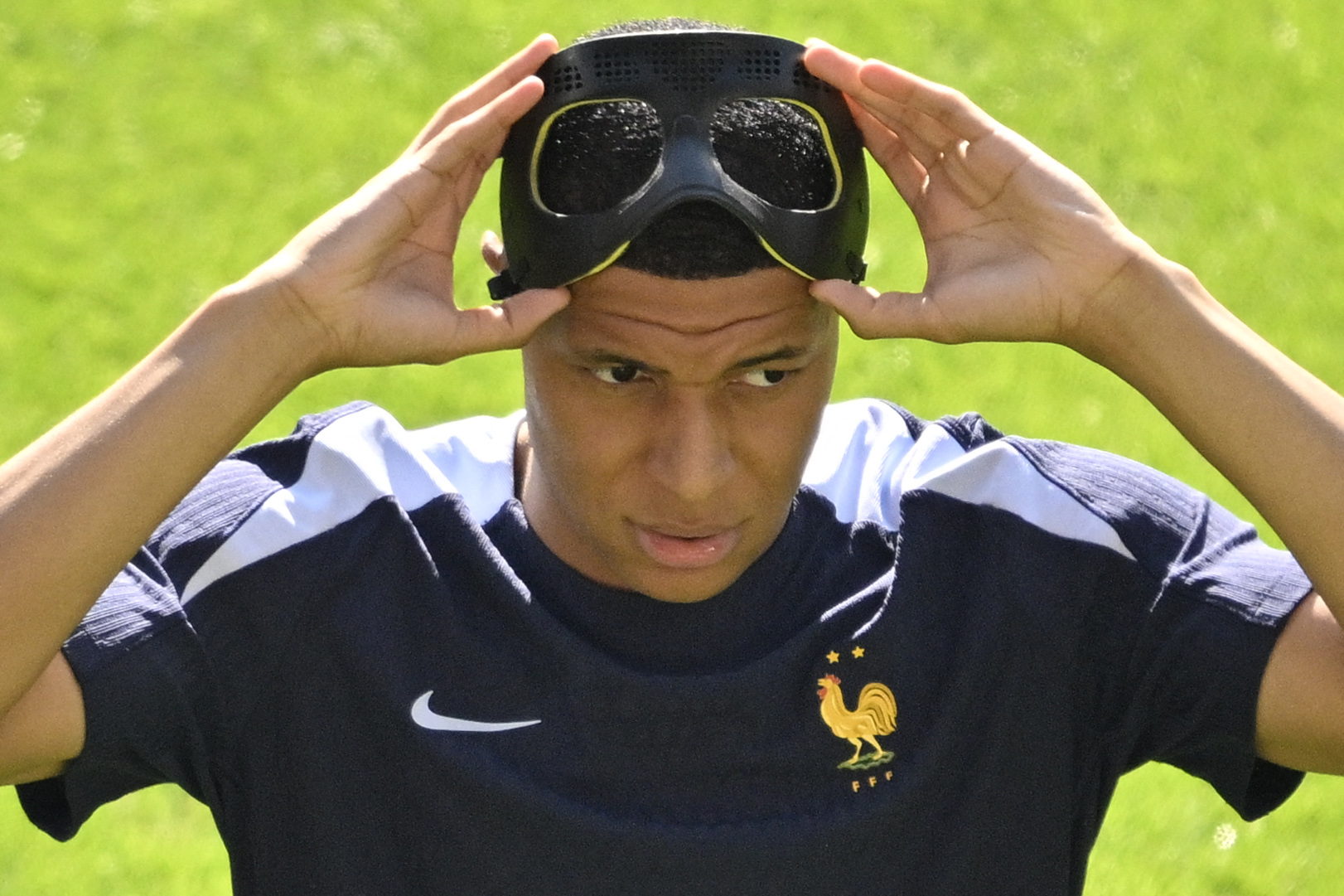 France's forward #10 Kylian Mbappe puts on his protective mask as he takes part in a warm-up session prior to the UEFA Euro 2024 Group D football match between France and Poland at the BVB Stadion in Dortmund on June 25, 2024. (Photo by INA FASSBENDER / AFP)