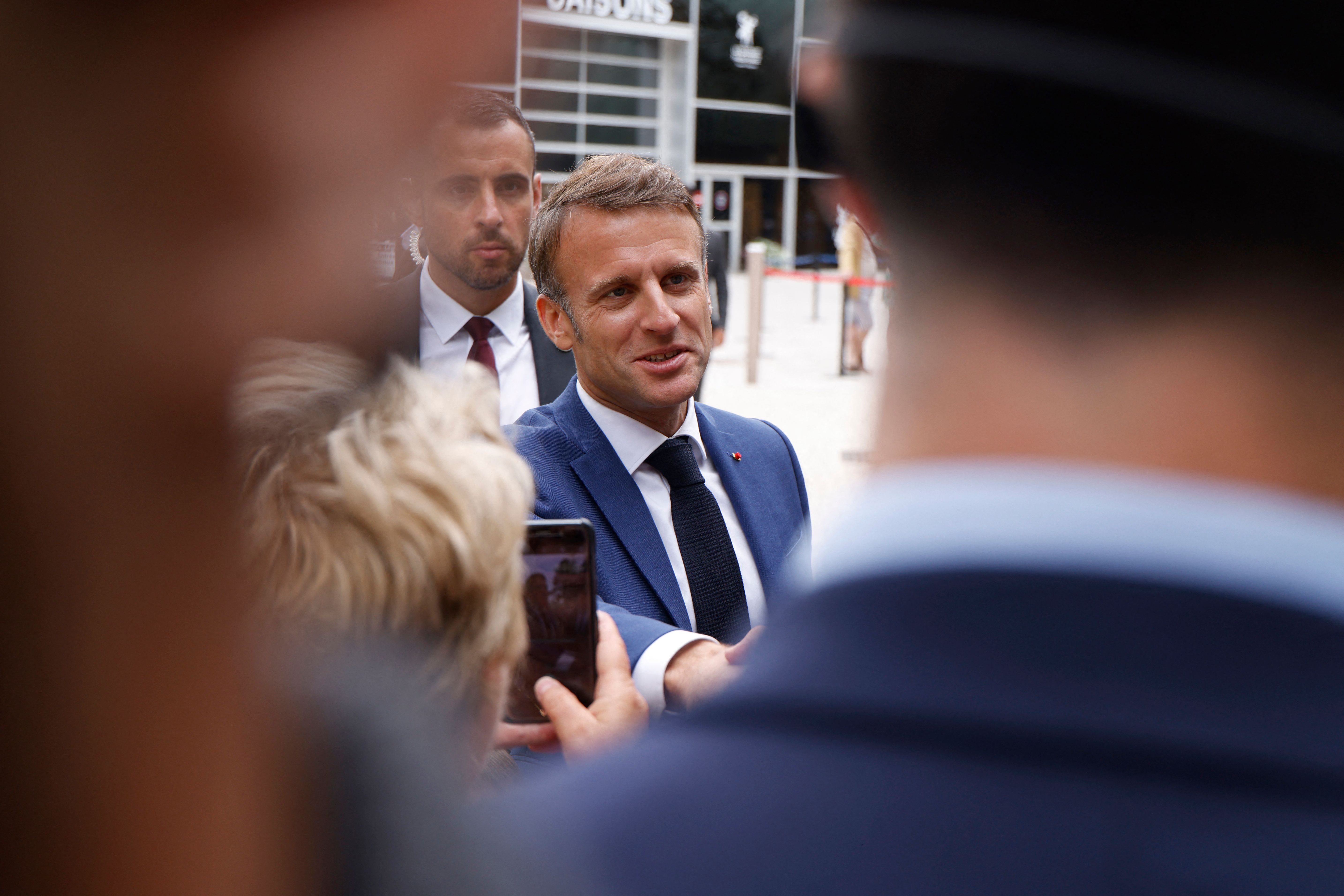 France's President Emmanuel Macron shakes hands with supporters after voting in the first round of parliamentary elections outside a polling station in Le Touquet, northern France on June 30, 2024. A divided France is voting in high-stakes parliamentary elections that could see the anti-immigrant and eurosceptic party of Marine Le Pen sweep to power in a historic first. The candidates formally ended their frantic campaigns at midnight June 28, with political activity banned until the first round of voting. (Photo by Ludovic MARIN / AFP)