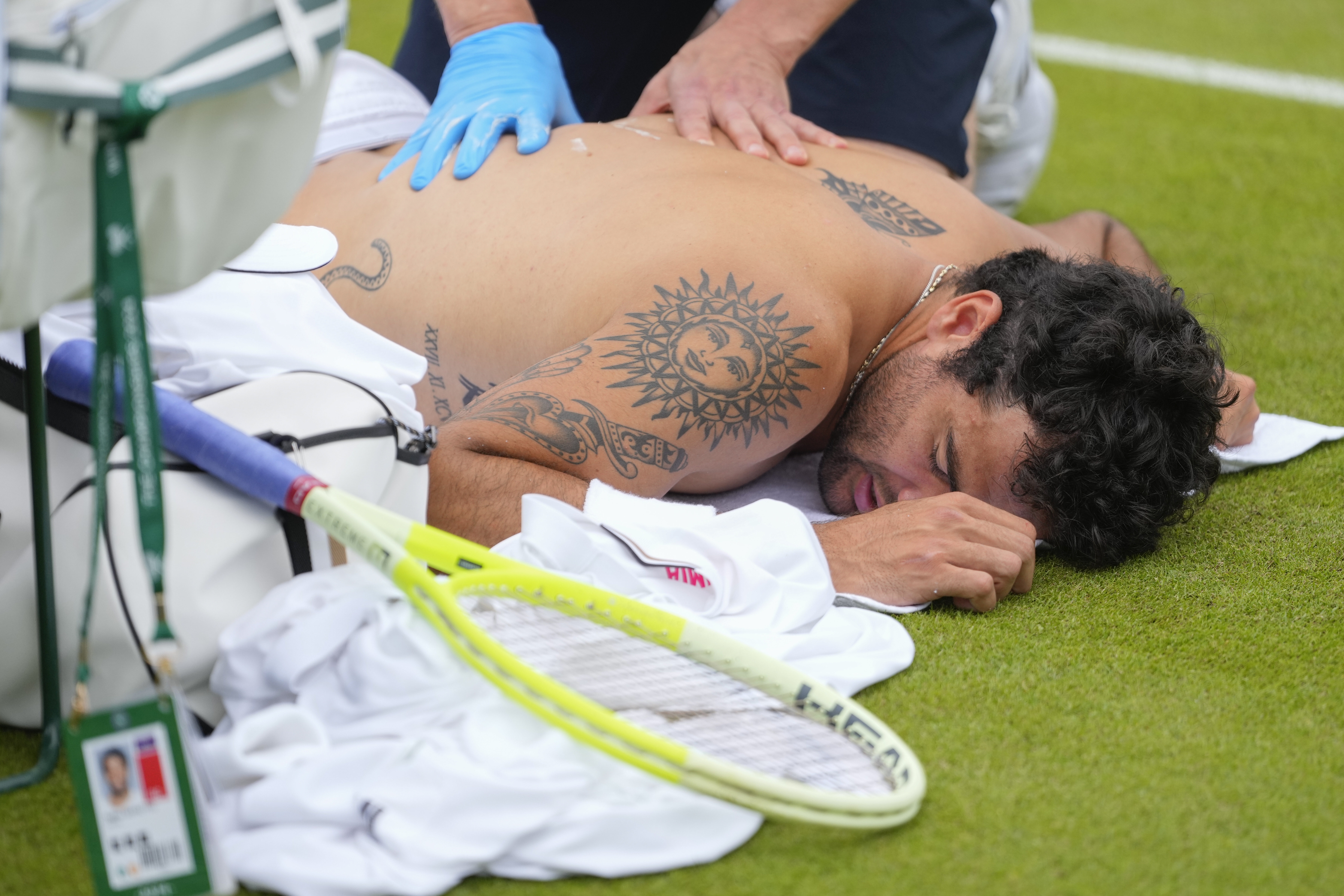 Matteo Berrettini of Italy receives medical treatment during his first round match against Marton Fucsovics of Hungary at the Wimbledon tennis championships in London, Monday, July 1, 2024. (AP Photo/Kirsty Wigglesworth)