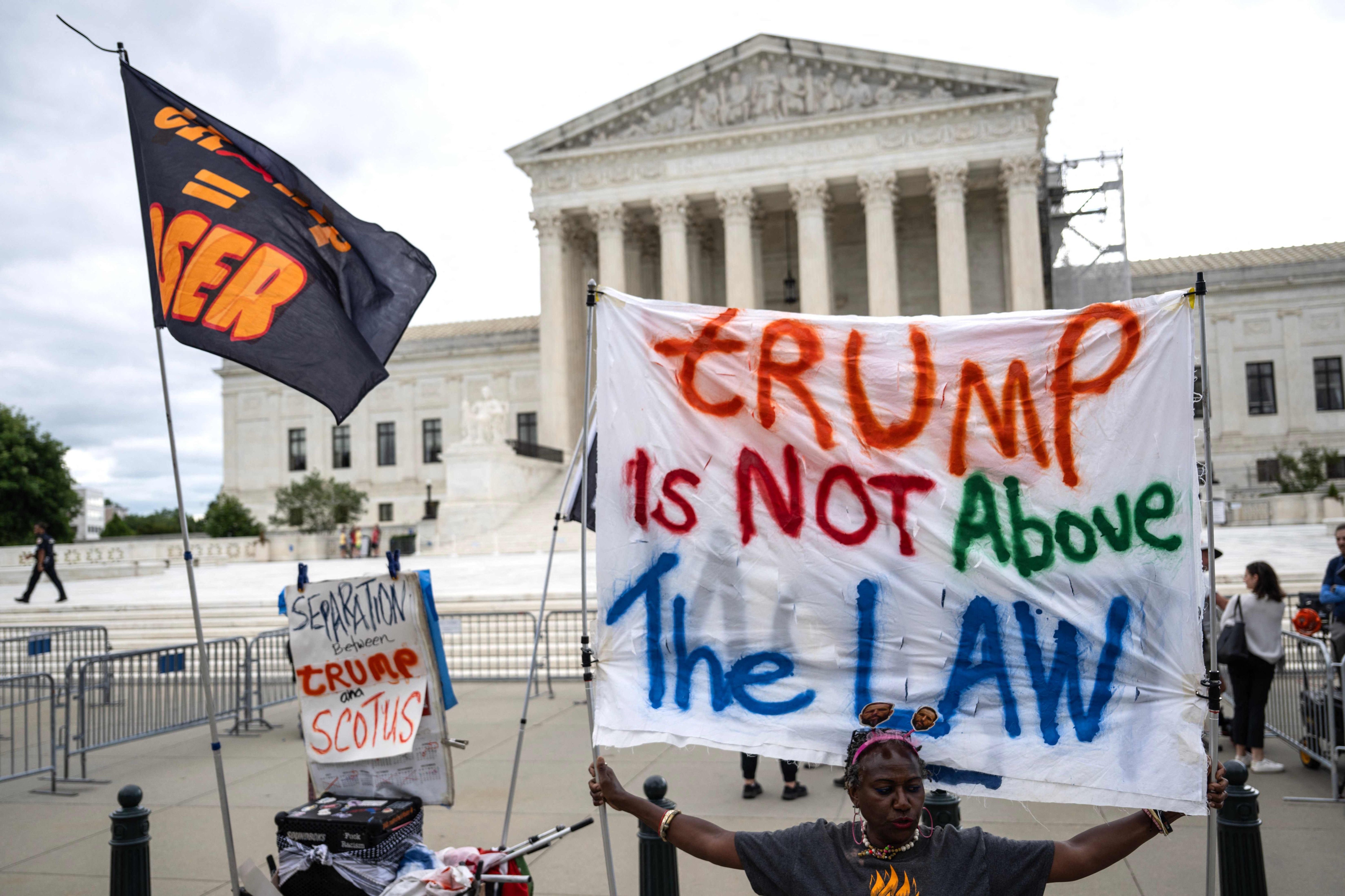People hold anti-Trump signs in front of the US Supreme Court on July 1, 2024, in Washington, DC. Donald Trump on Monday hailed a "big win" for democracy after the US Supreme Court ruled that presidents have presumptive immunity for official acts -- a decision set to delay his trial for conspiring to overturn his 2020 election loss. (Photo by Drew ANGERER / AFP)