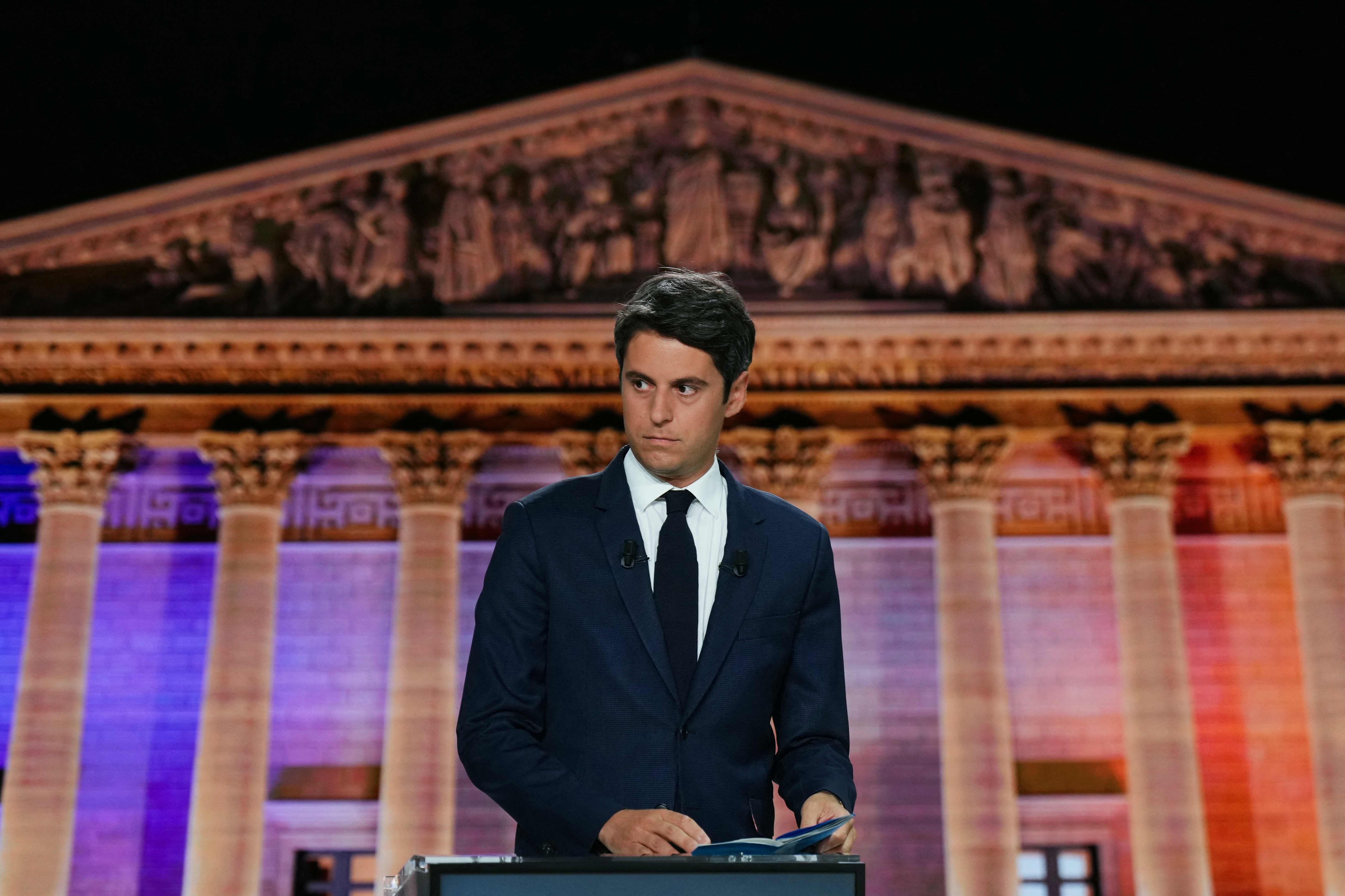 French Prime Minister Gabriel Attal stands behind his lactern prior to the start of a political debate with First Secretary of the French left-wing Socialist Party (PS) and member of parliament Olivier Faure and French far-right Rassemblement National (RN) party President and lead MEP Jordan Bardella broadcasted on French TV channel France 2, in Paris on June 27, 2024, ahead of France's snap elections for a new national assembly. (Photo by Dimitar DILKOFF / POOL / AFP)