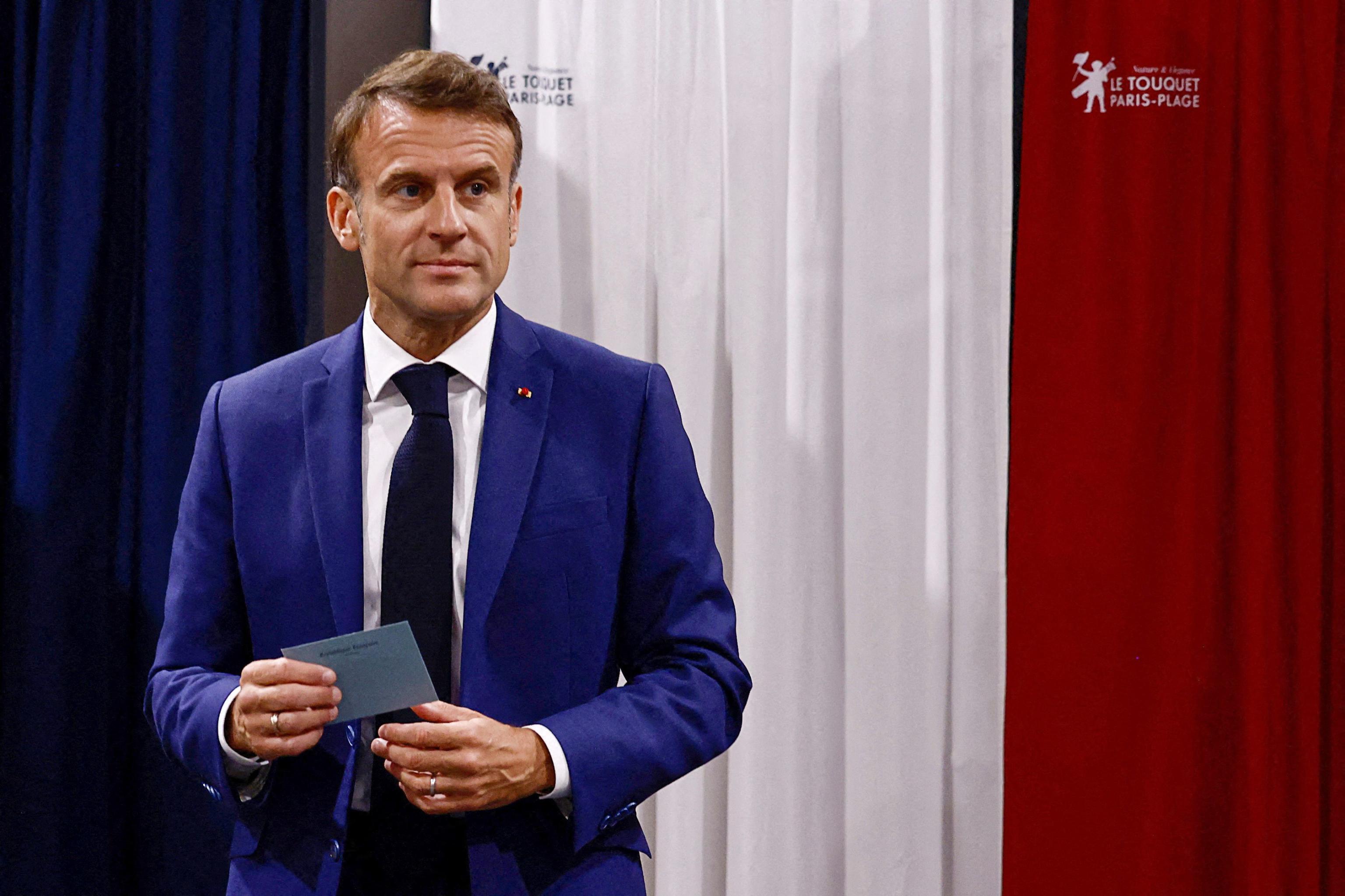 TOPSHOT - France's President Emmanuel Macron leaves the polling booth prior to cast his vote in the first round of parliamentary elections at a polling station in Le Touquet, northern France on June 30, 2024. A divided France is voting in high-stakes parliamentary elections that could see the anti-immigrant and eurosceptic party of Marine Le Pen sweep to power in a historic first. The candidates formally ended their frantic campaigns at midnight June 28, with political activity banned until the first round of voting. (Photo by Yara Nardi / POOL / AFP)