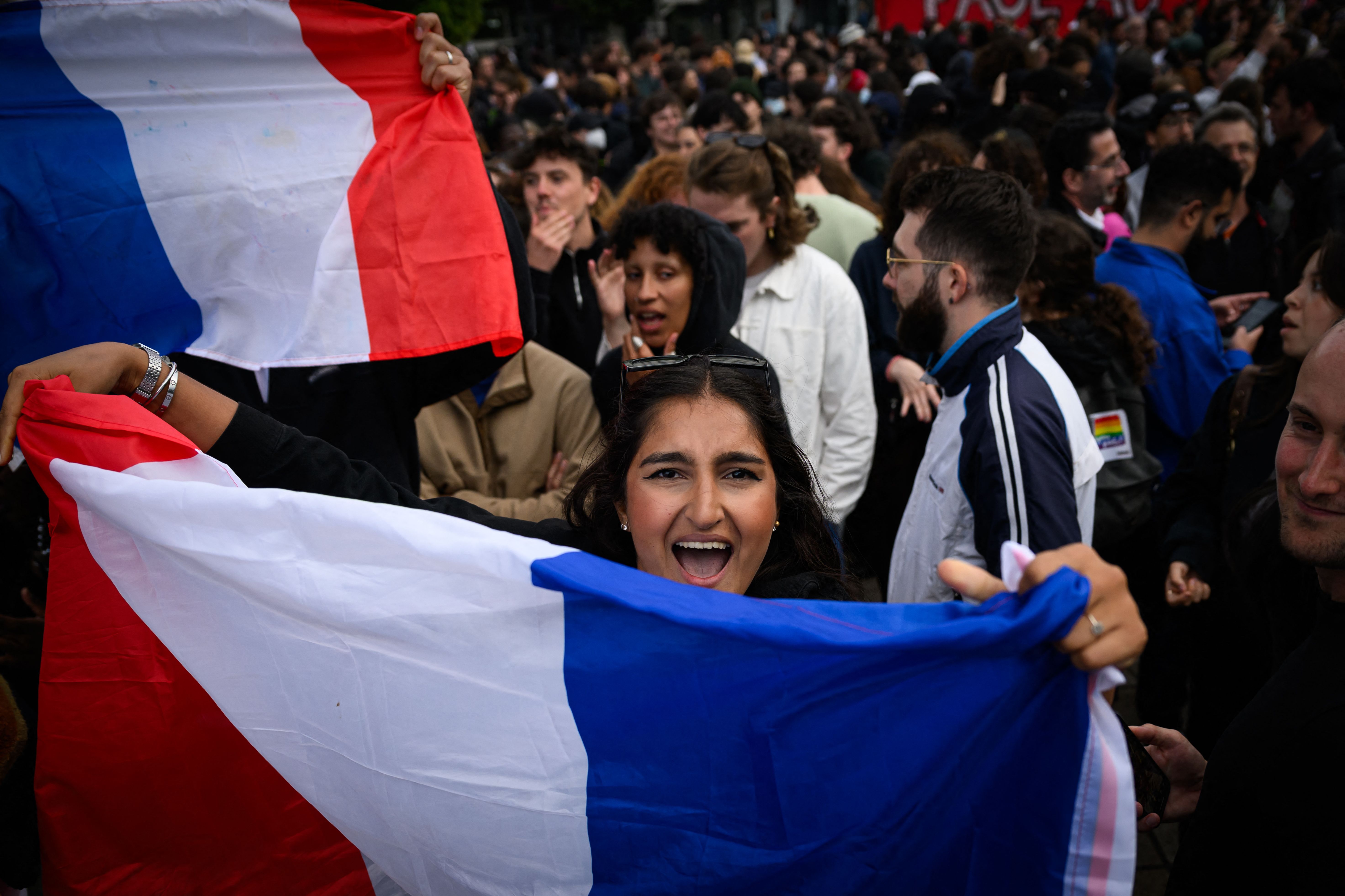 A partcipant holds a French national flag during a demonstration following the announcement of the projected results of the second round of Frances crunch legislative elections during a rally in Nantes, western France on July 7, 2024. A loose alliance of French left-wing parties thrown together for snap elections was on course to become the biggest parliamentary bloc and beat the far right, according to shock projected results. (Photo by Loic VENANCE / AFP)