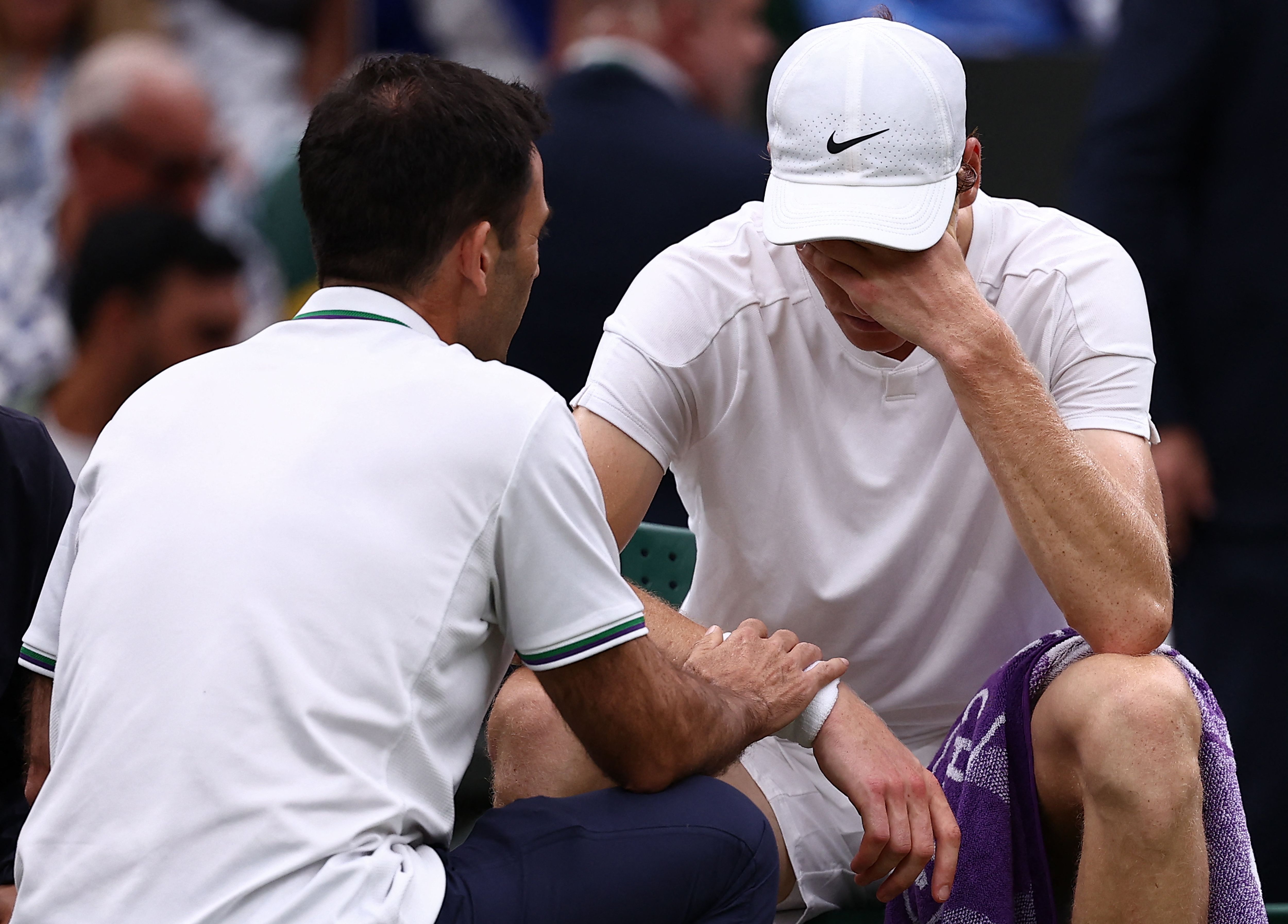 Italy's Jannik Sinner talks to staff during a medical time-out in his match against Russia's Daniil Medvedev during their men's singles quarter-final tennis match on the ninth day of the 2024 Wimbledon Championships at The All England Lawn Tennis and Croquet Club in Wimbledon, southwest London, on July 9, 2024. (Photo by HENRY NICHOLLS / AFP) / RESTRICTED TO EDITORIAL USE