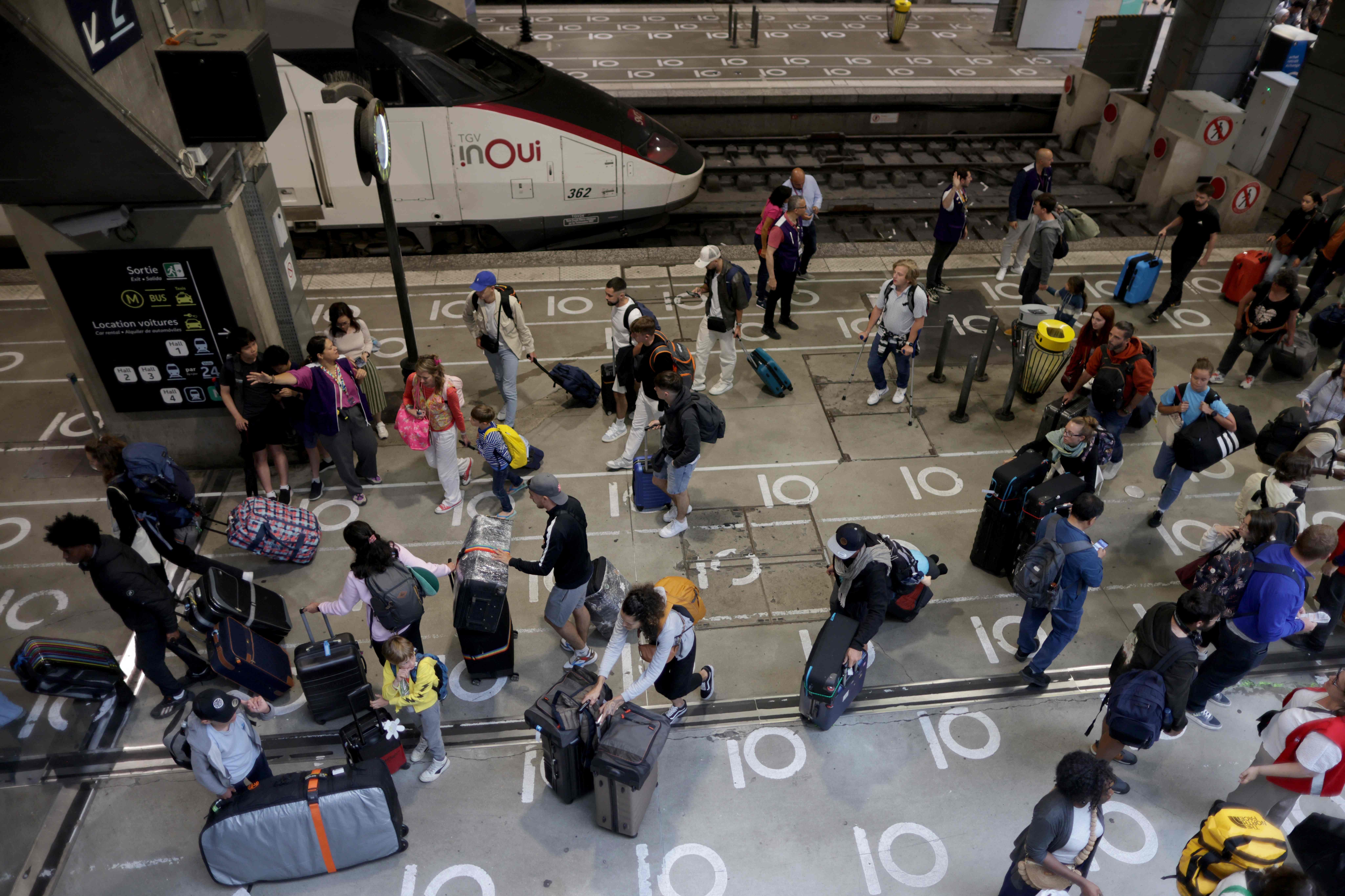 Passengers walk on a platform at the Gare Montparnasse train station in Paris on July 26, 2024 as France's high-speed rail network was hit by malicious acts disrupting the transport system hours before the opening ceremony of the Paris 2024 Olympic Games. According to SNCF a massive attack on a large scale hit the TGV network and many routes will have to be cancelled. SNCF urged passengers to postpone their trips and stay away from train stations. (Photo by Thibaud MORITZ / AFP)