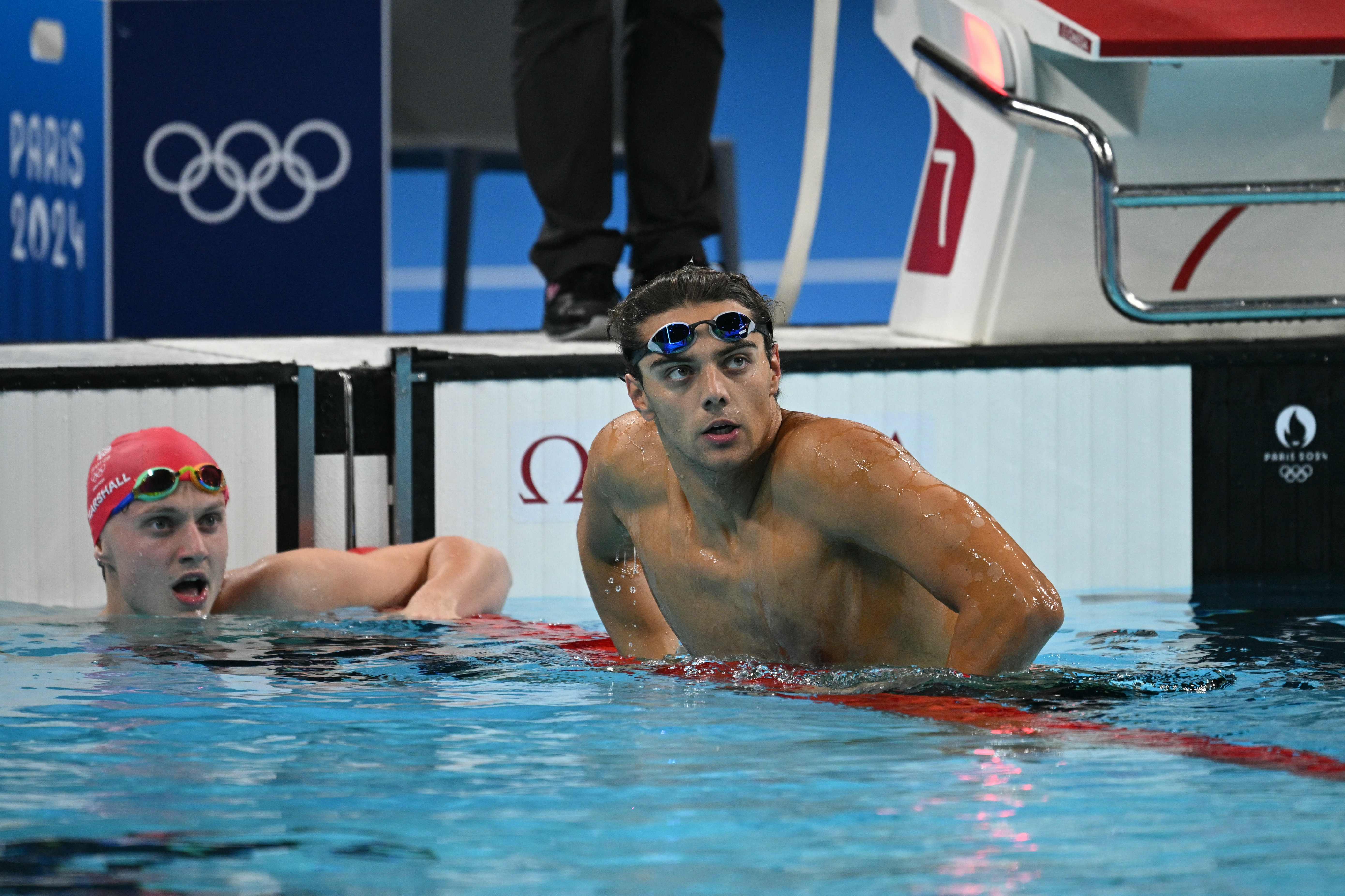 Italy's Thomas Ceccon (R) and Britain's Jonny Marshall react after a semifinal of the men's 100m backstroke swimming event during the Paris 2024 Olympic Games at the Paris La Defense Arena in Nanterre, west of Paris, on July 28, 2024. (Photo by Oli SCARFF / AFP)