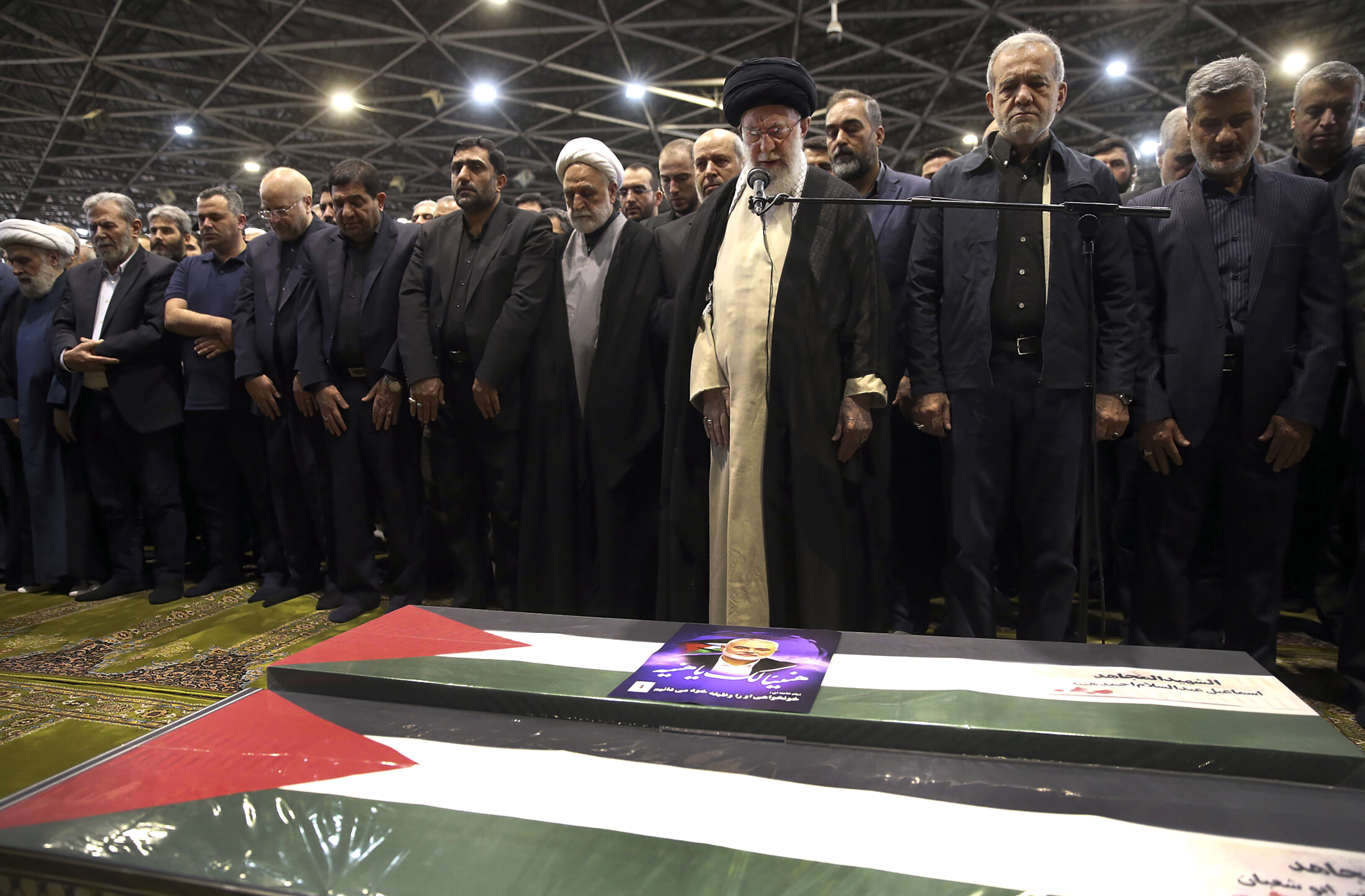 In this photo released by the official website of the office of the Iranian supreme leader, Supreme Leader Ayatollah Ali Khamenei, third right, leads a prayer over the coffins of Hamas leader Ismail Haniyeh and his bodyguard who were killed in an assassination blamed on Israel on Wednesday, during their funeral ceremony at the Tehran University campus, in Tehran, Iran, Thursday, Aug. 1, 2024. Iranian President Masoud Pezeshkian prays at second right. (Office of the Iranian Supreme Leader via AP)