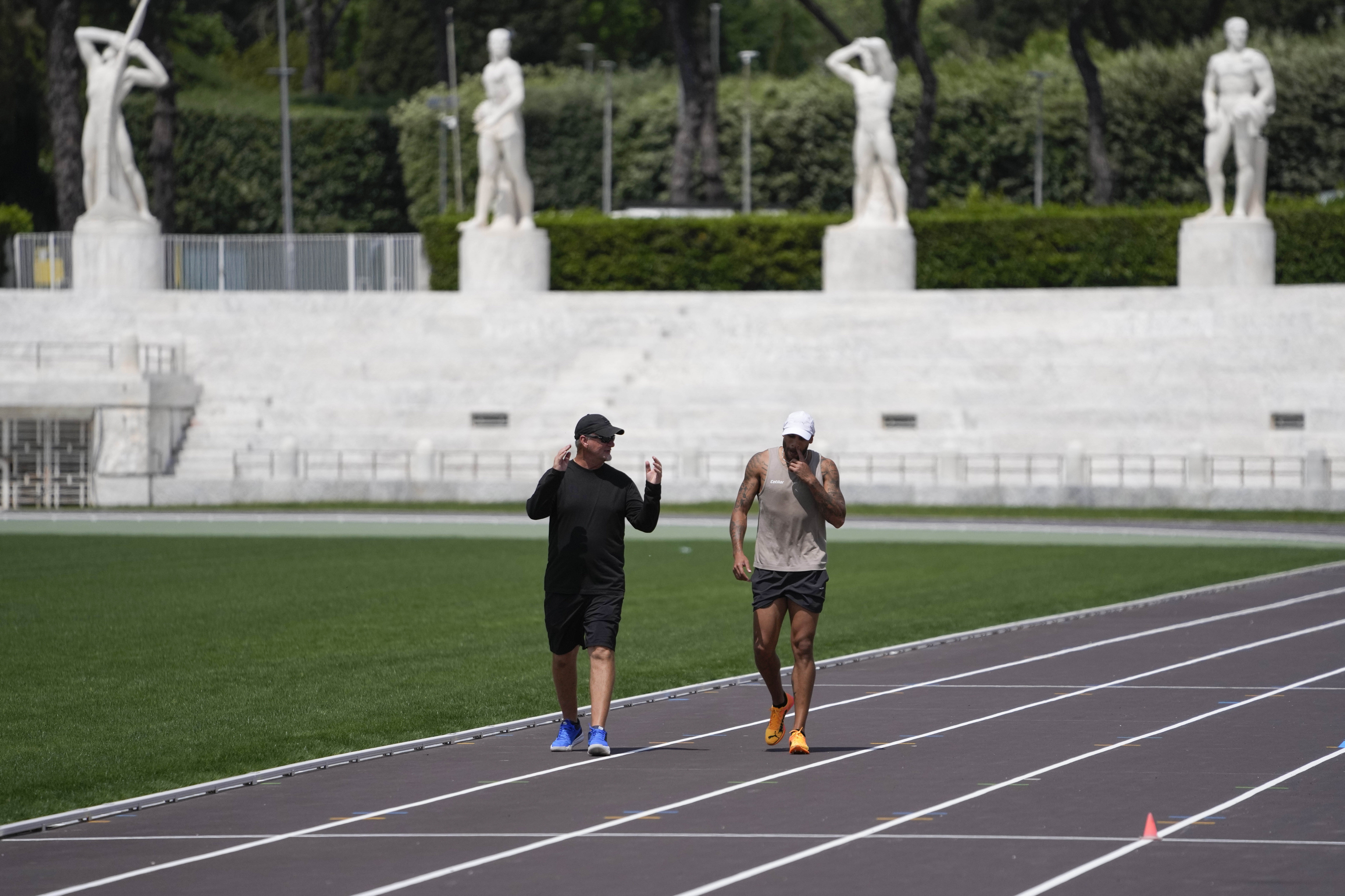Defending Olympic 100 meters champion Marcell Jacobs, right, talks with his coach Rana Reider during a training session in the historic Stadio dei Marmi ahead of an athletics meeting in Rome, Wednesday, May 15, 2024. (AP Photo/Alessandra Tarantino)