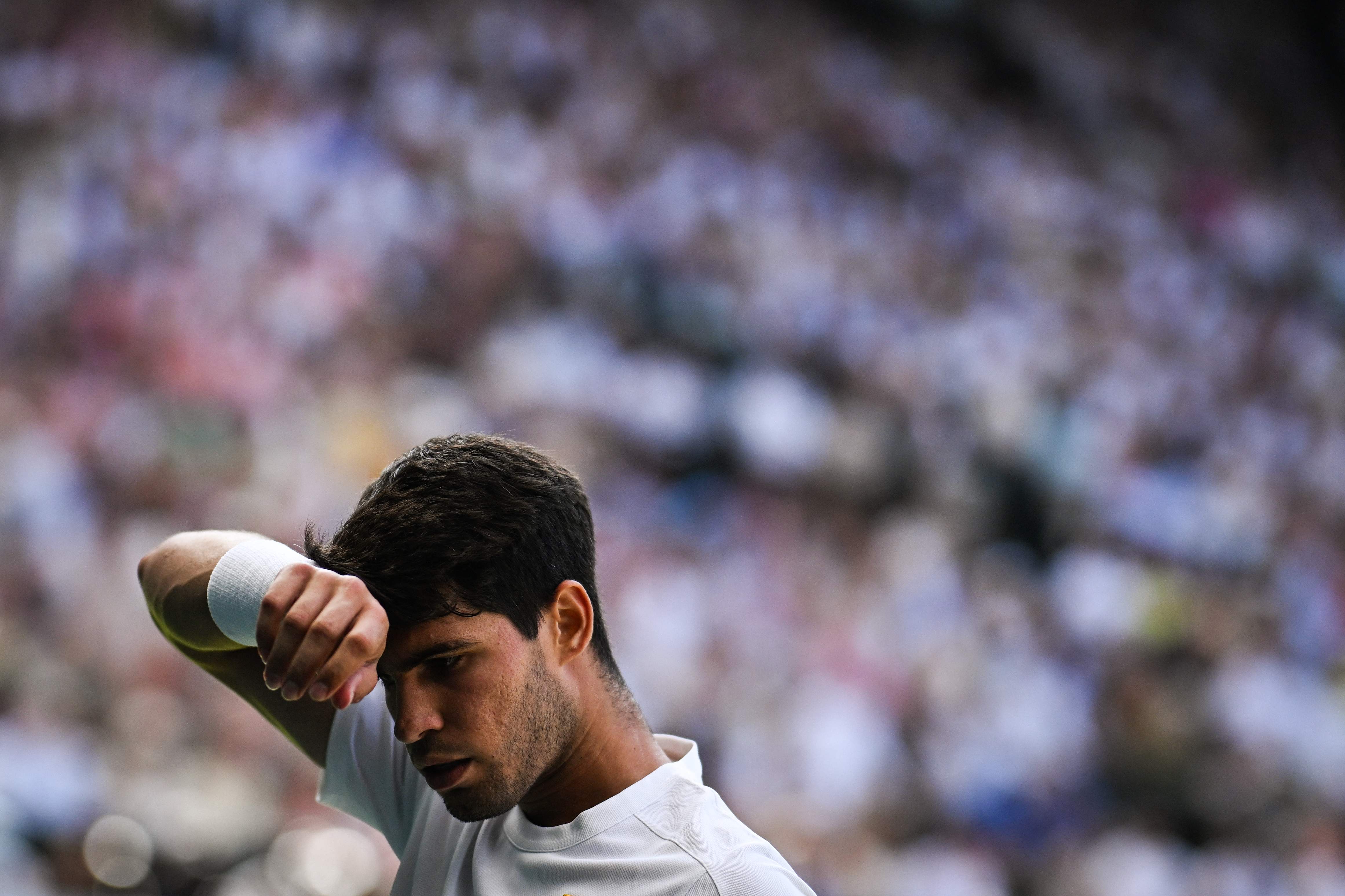 Spain's Carlos Alcaraz wipes his face as he plays against Italy's Jannik Sinner during their men's singles final tennis match on the fourteenth day of the 2025 Wimbledon Championships at The All England Lawn Tennis and Croquet Club in Wimbledon, southwest London, on July 13, 2025. (Photo by Kirill KUDRYAVTSEV / AFP) / RESTRICTED TO EDITORIAL USE