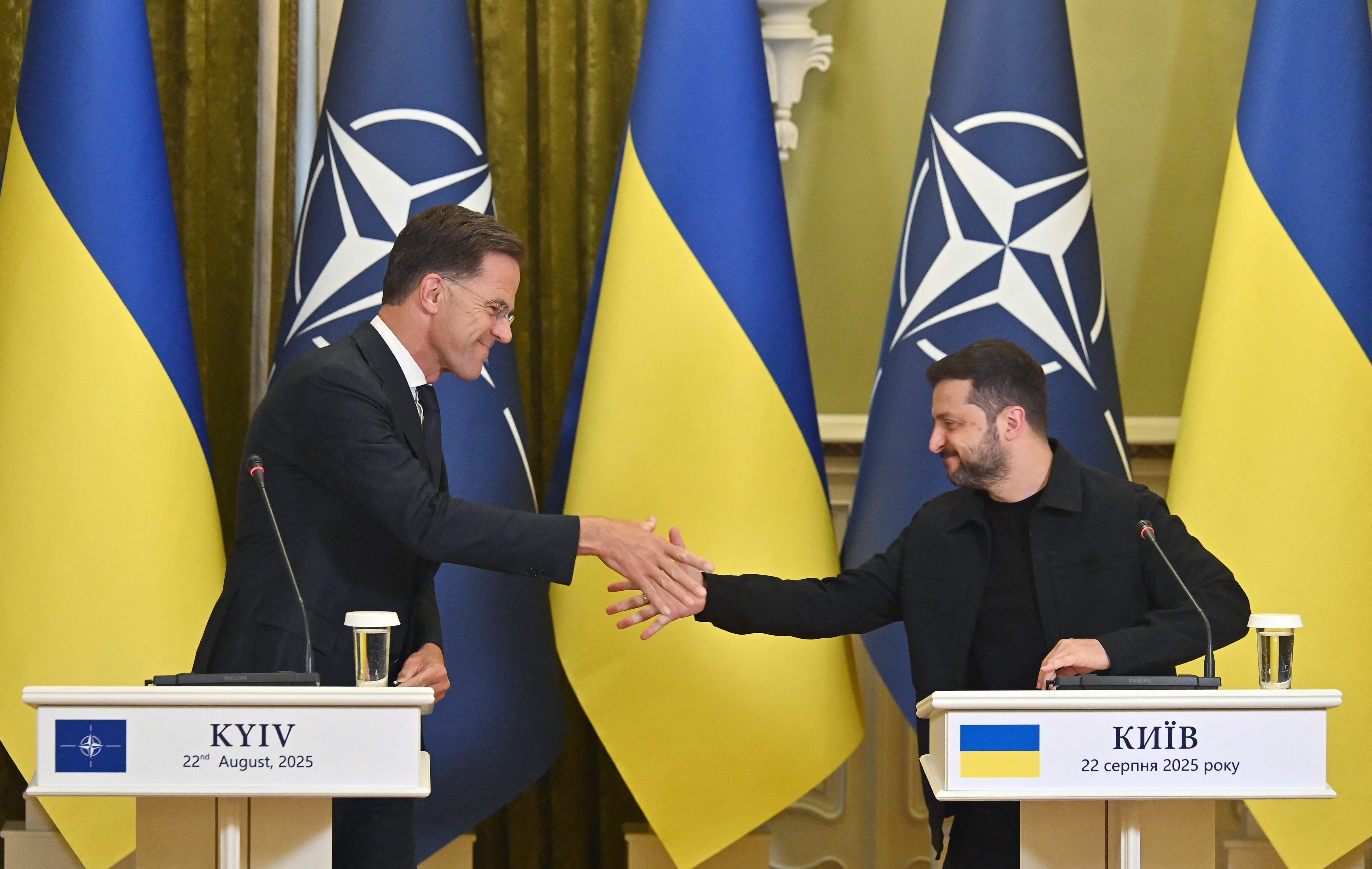 Ukraine's President Volodymyr Zelensky (R) and Secretary General of NATO Mark Rutte shake hands during their press-conference following their talks in Kyiv on August 22, 2025, amid Russian invasion of Ukraine. (Photo by Sergei SUPINSKY / AFP)